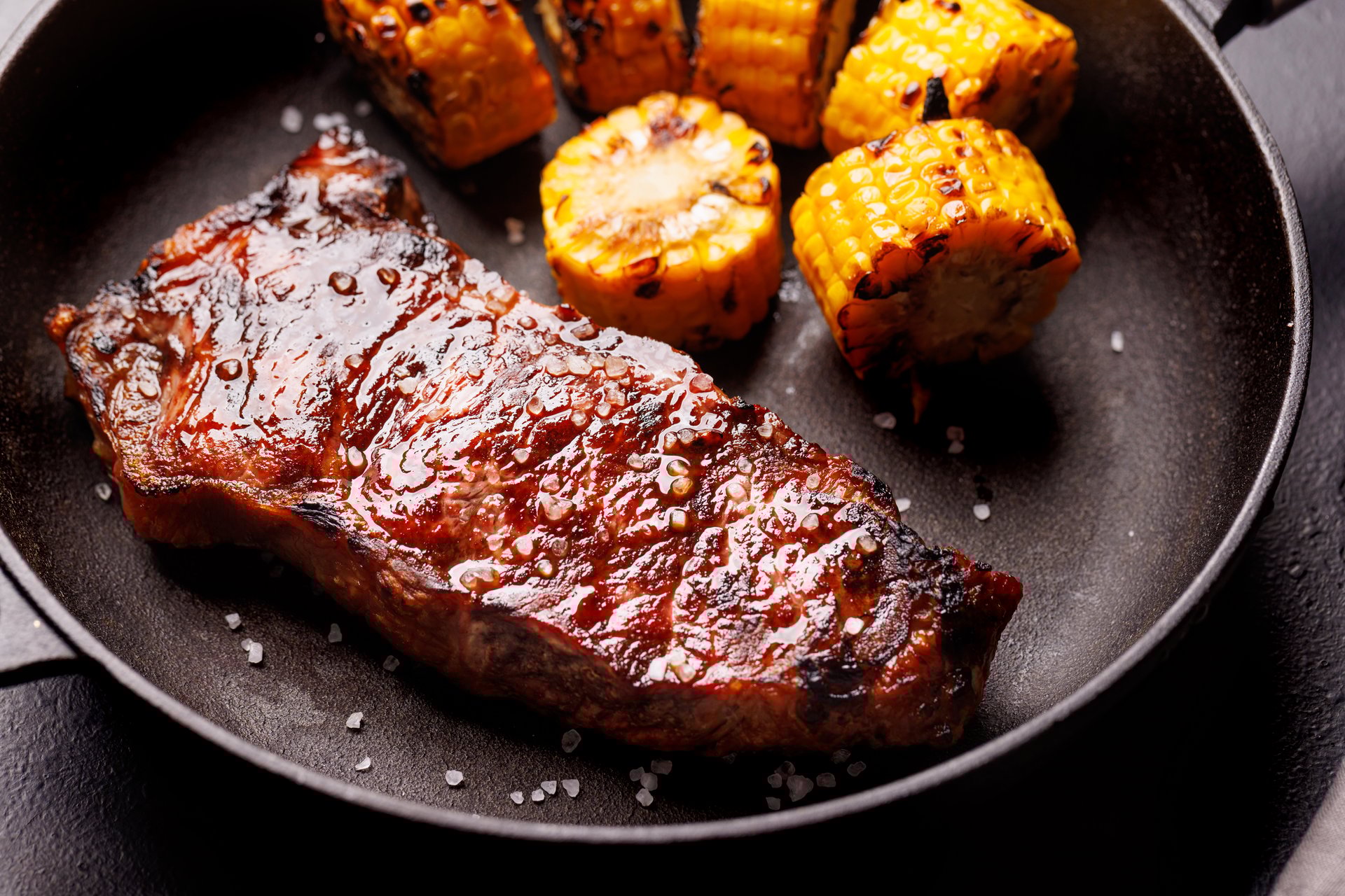 A perfectly cooked striploin steak with a juicy, tender texture on a dark background. A gourmet meal for steak and wine lovers