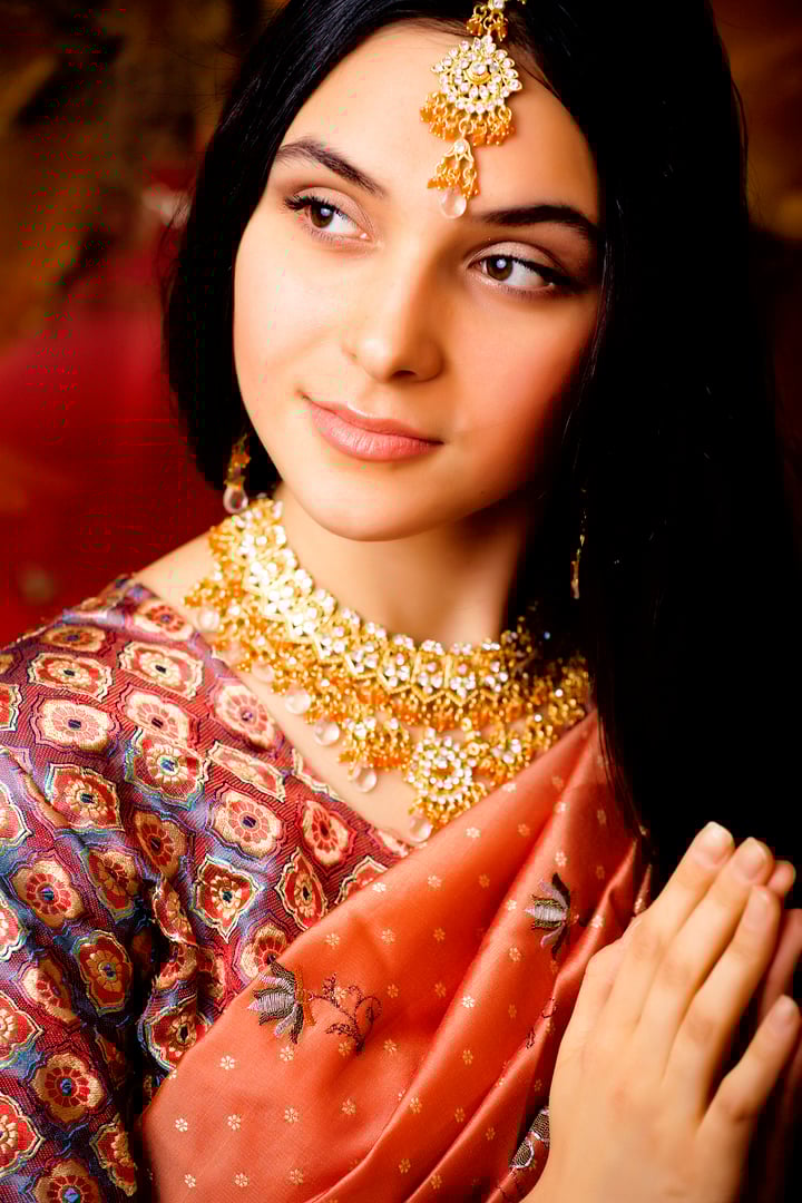 beauty sweet real indian girl in sari smiling on black background, jewelry shining