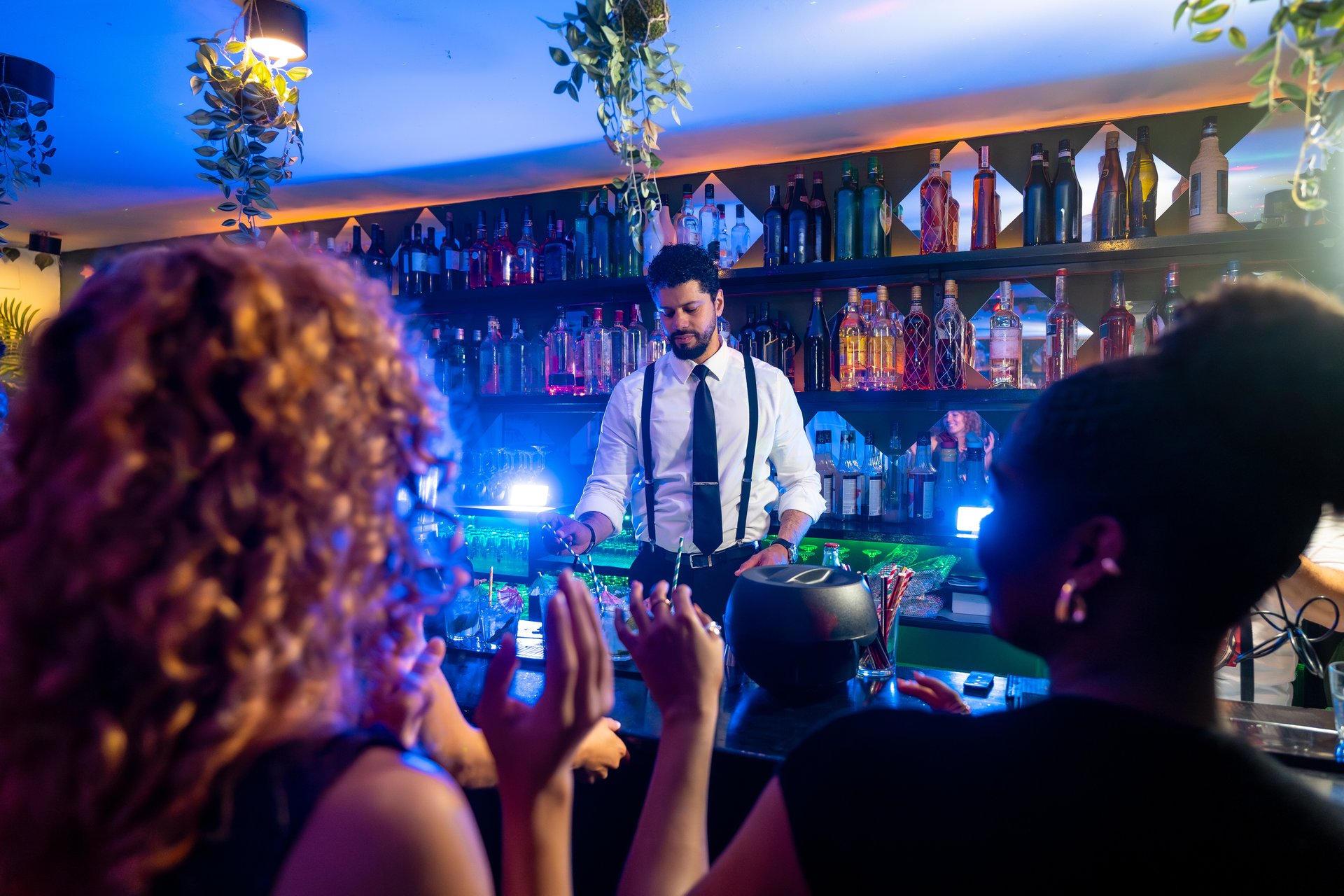 Bartender prepares cocktails for customers at a bar counter, showcasing the nightlife and entertainment industry