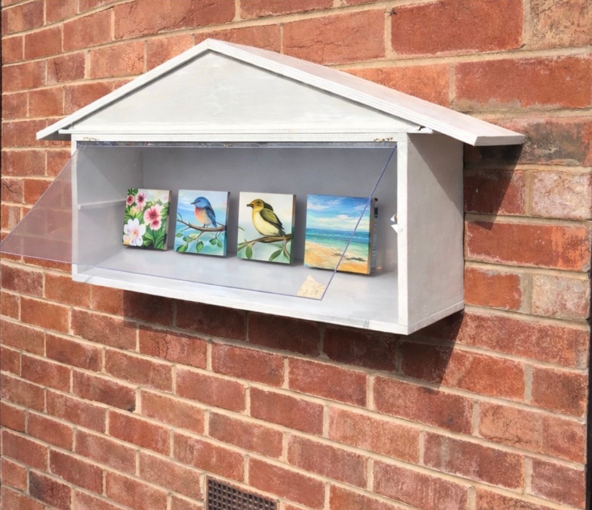 The Little Pocket Gallery illuminated at dusk with internal light glowing