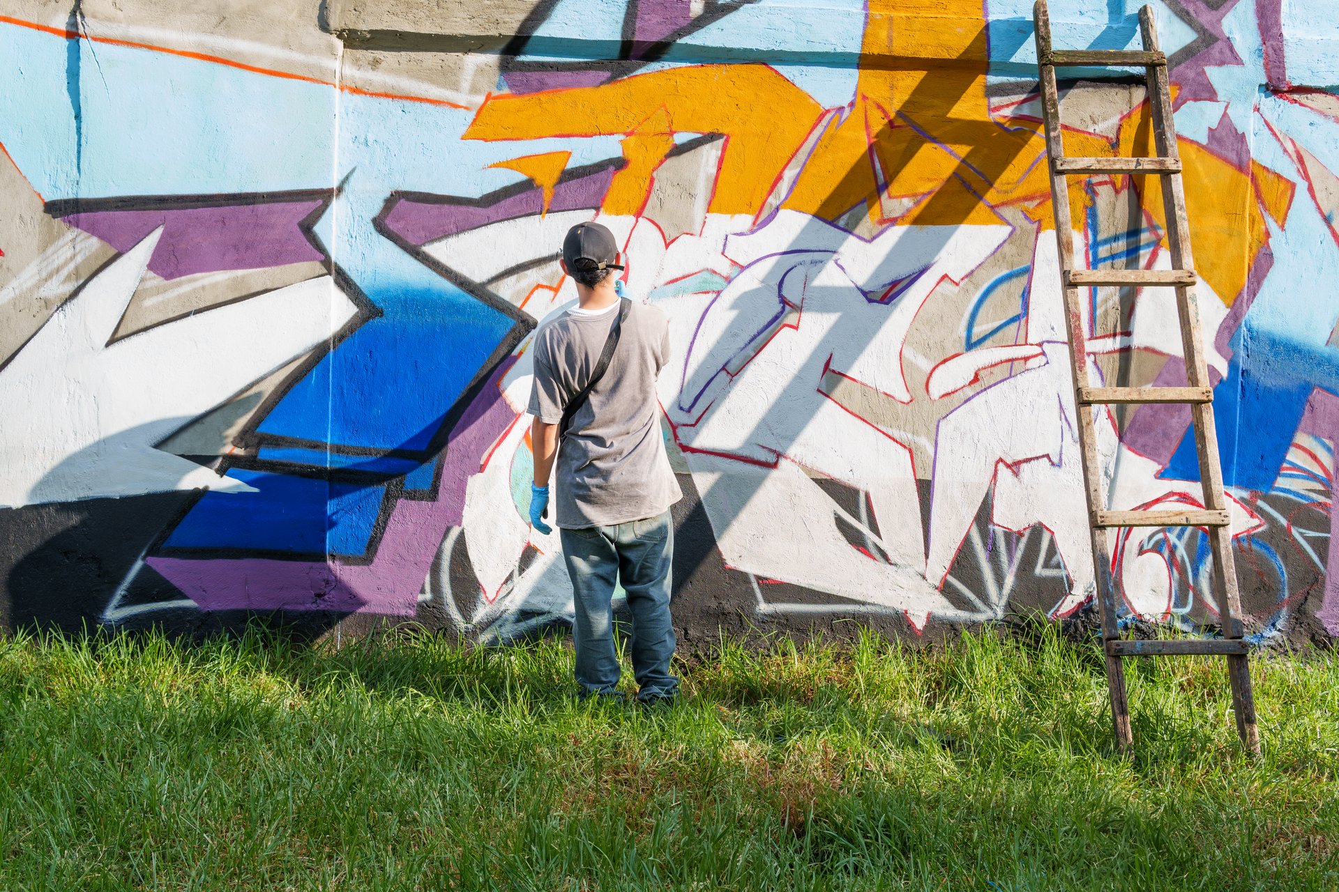 Graffiti artist painting colorful street art on a concrete wall using spray paint, showcasing urban creativity and self-expression