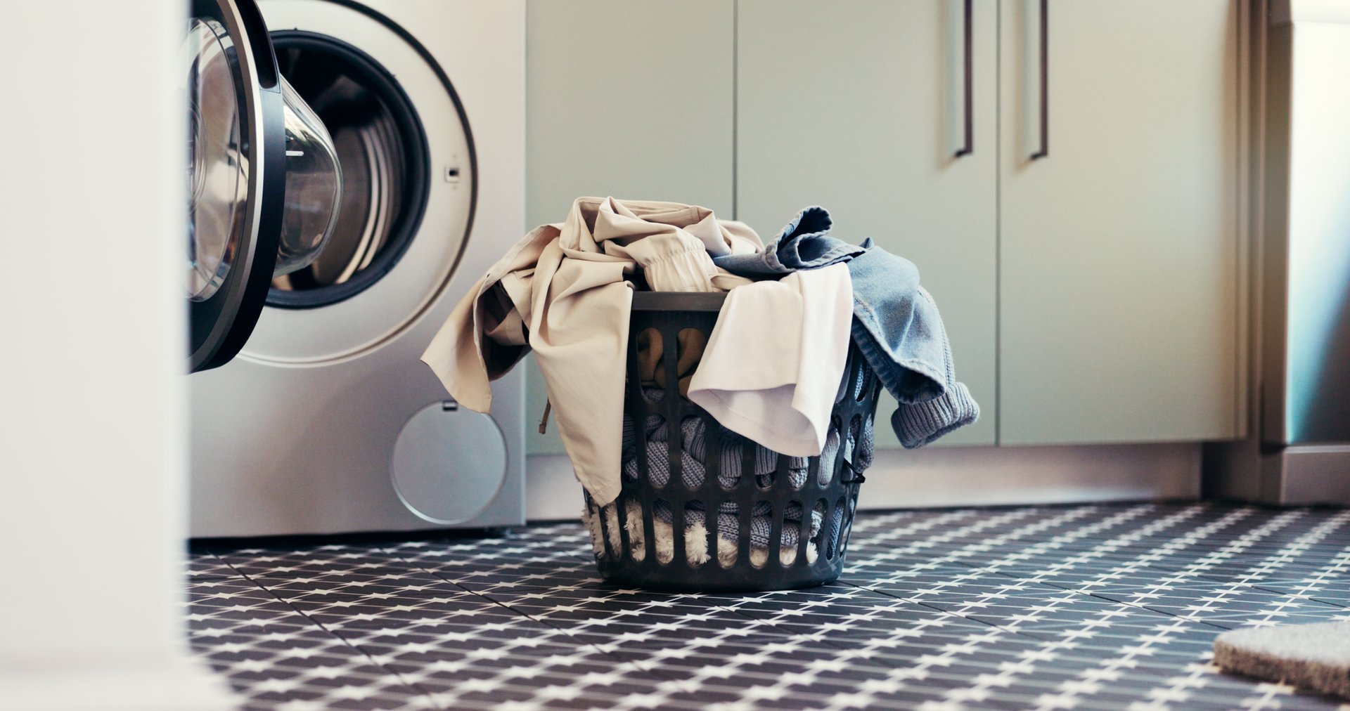 Laundry, washing machine and clothes in basket in home for housekeeping, fresh linen and hygiene. Empty, apartment and appliance with clean fabric for domestic chores, sanitation or housework routine