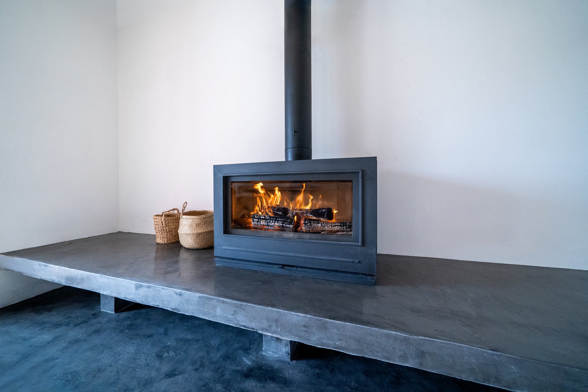 Fireplace inside house contemporany living room. Cosy living room with wood burner stove with burning flame behind a glass door