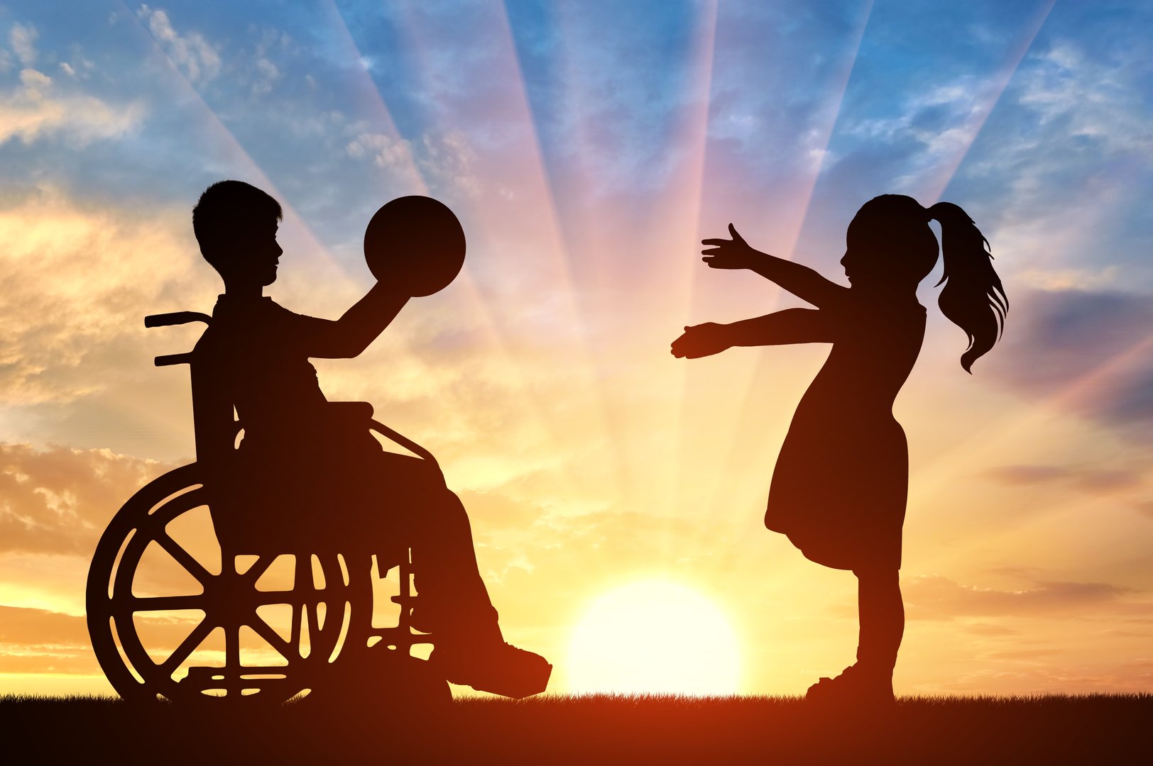 Silhouette of a boy in a wheelchair holding a ball and a girl eagerly reaching out to receive it. Ideal for themes related to disability awareness, diversity, and childhood happiness