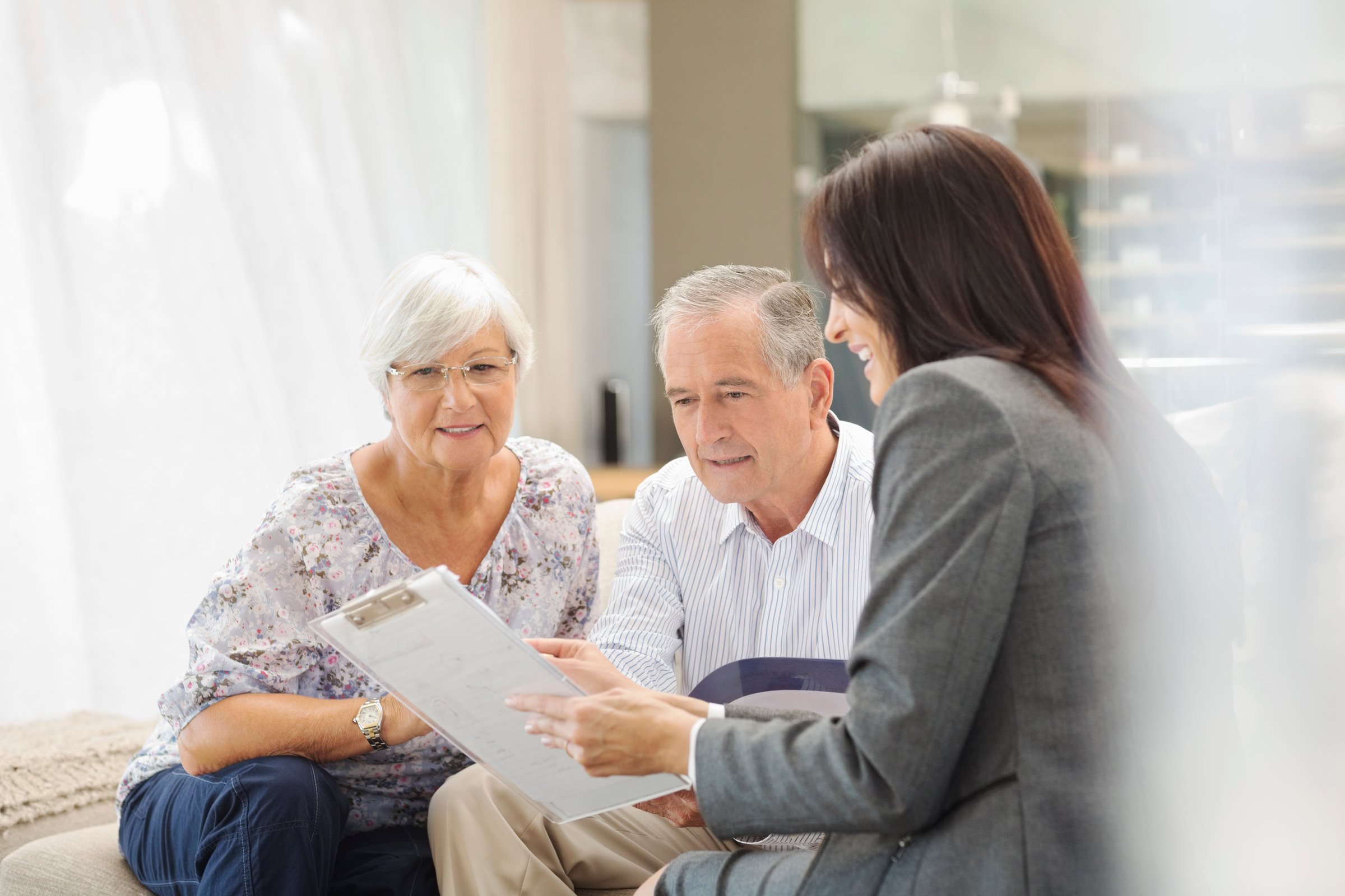 Elderly couple discussing paperwork with a professional woman in an office setting.