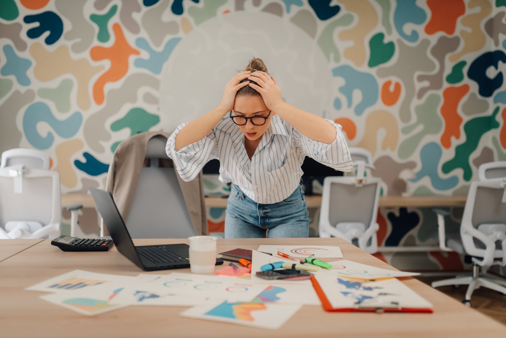 Young businesswoman experiencing stress and burnout while working on a project at her desk in a modern office