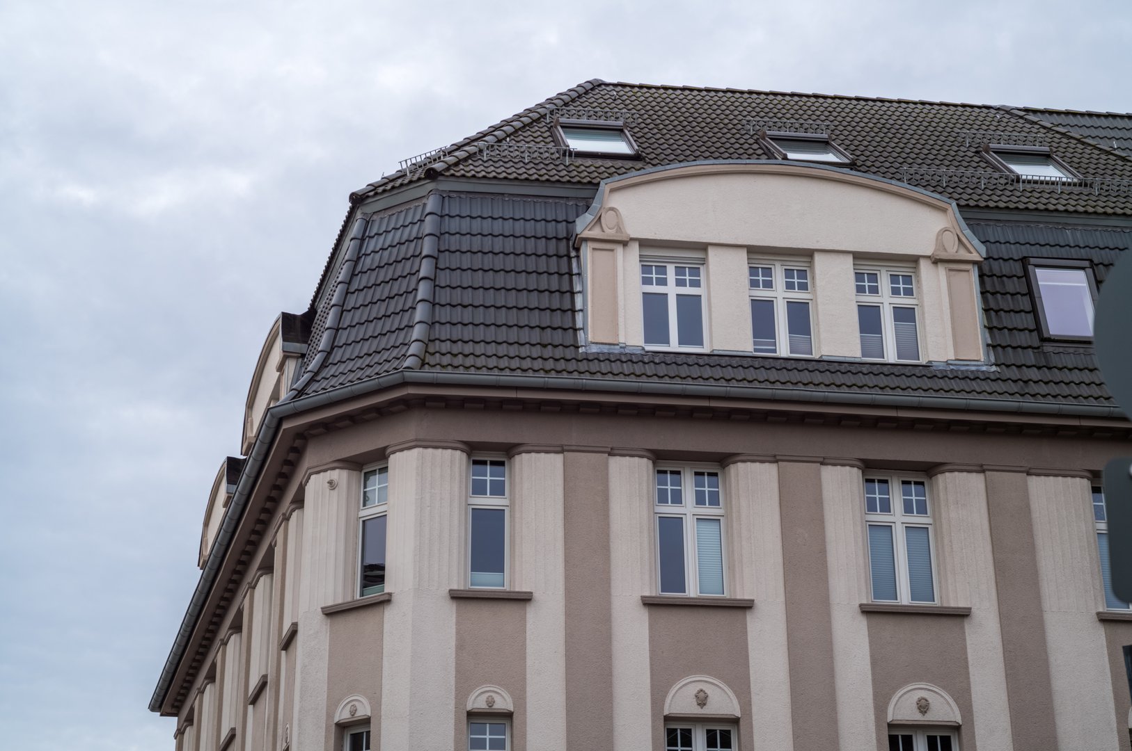 Elegant building showcasing a mansard roof with dormer windows and pilasters, reflecting elements of classical architecture
