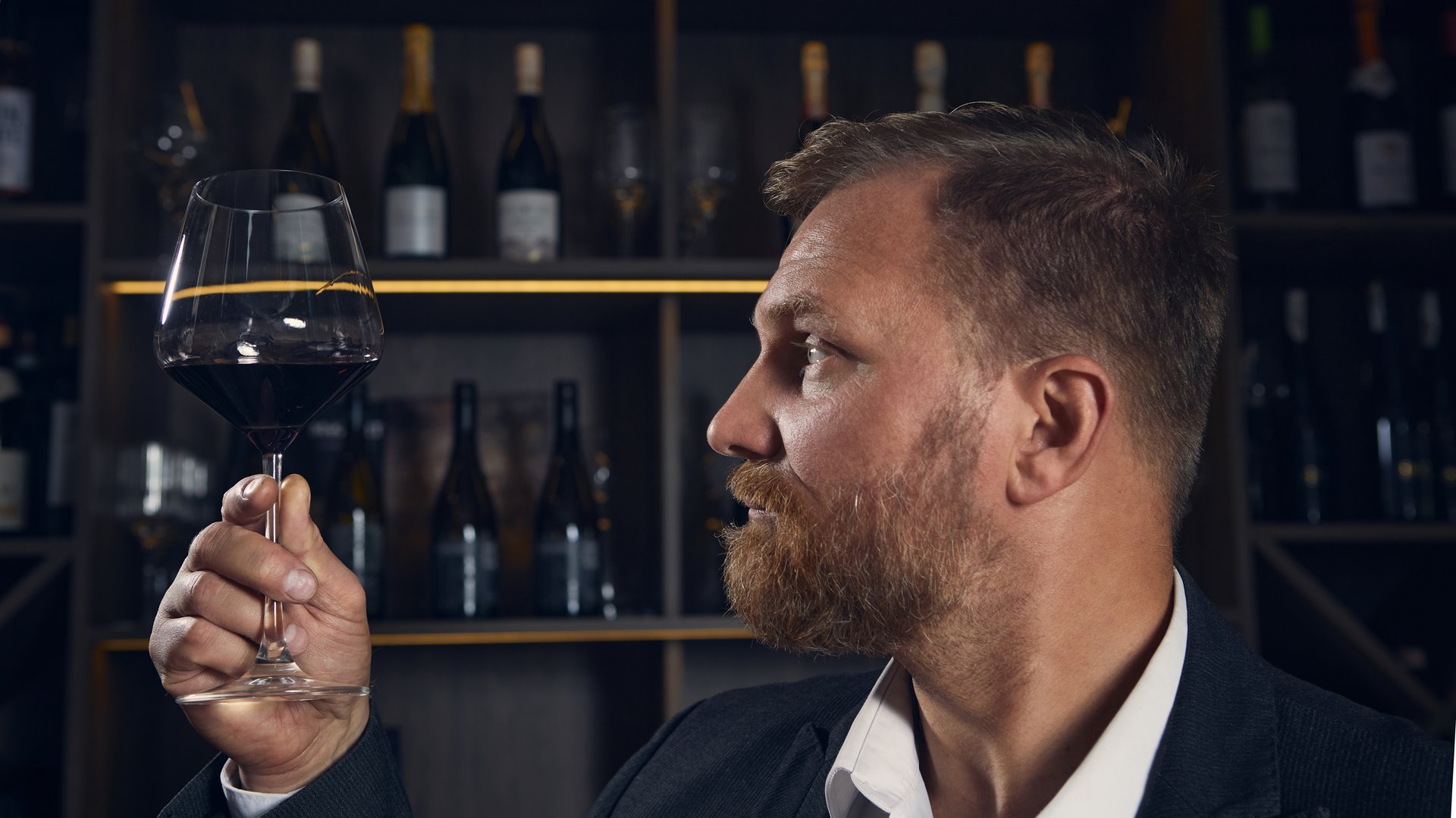 Sommelier examining color of wine in glass under warm light. Concept of professional focus, education, and sensory analysis combining precision with calm emotion.