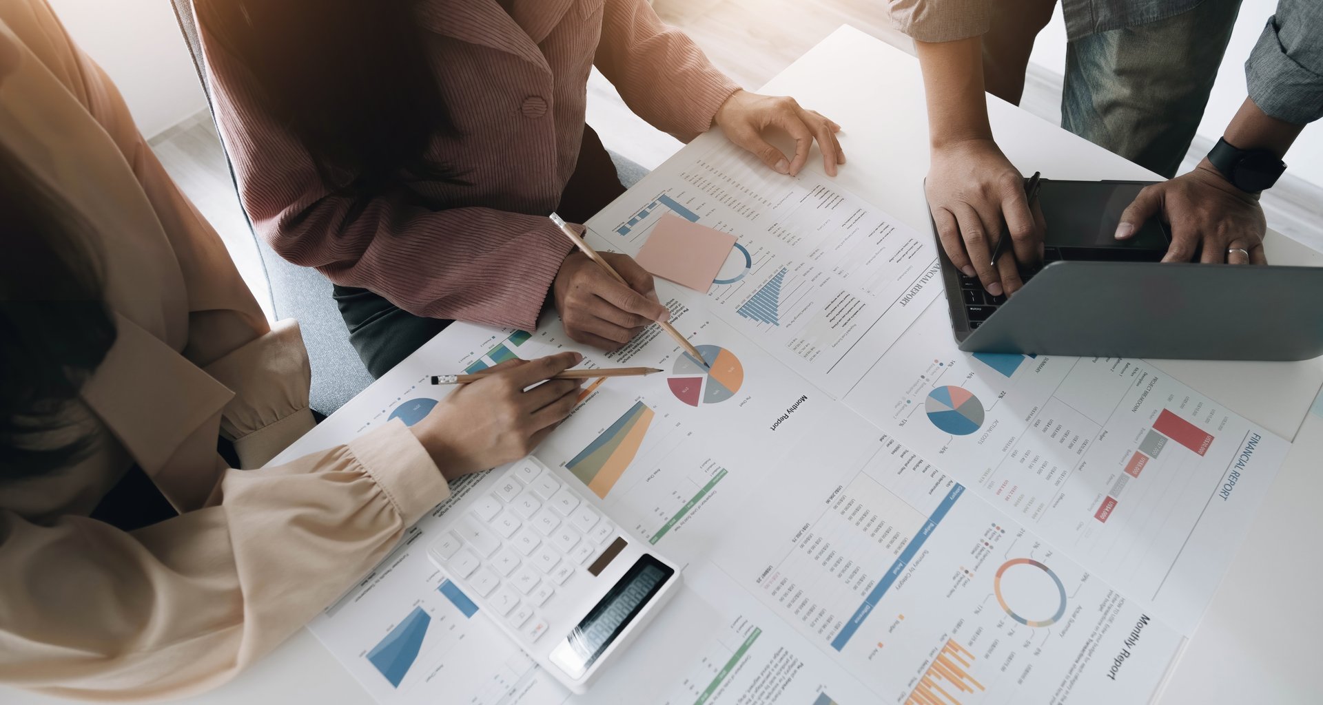 Business People Meeting using laptop computer, calculator,notebook,stock market chart paper for analysis Plans to improve quality next month. Conference Discussion Corporate Concept