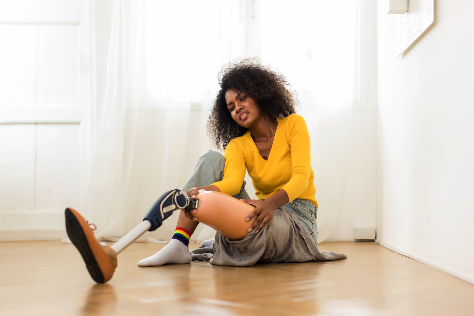 Woman with prosthetic leg doing physical therapy exercise at home. Woman wearing prosthetic equipment for walking.