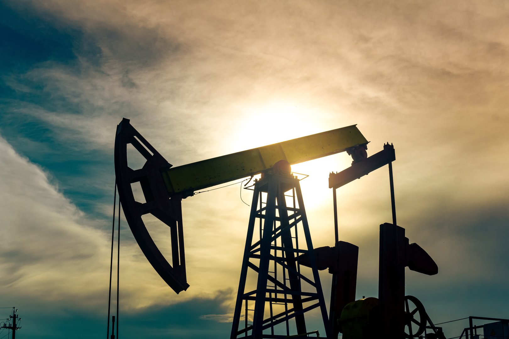 silhouette of a pumpjack with piston pump on an oil well against the background of sky