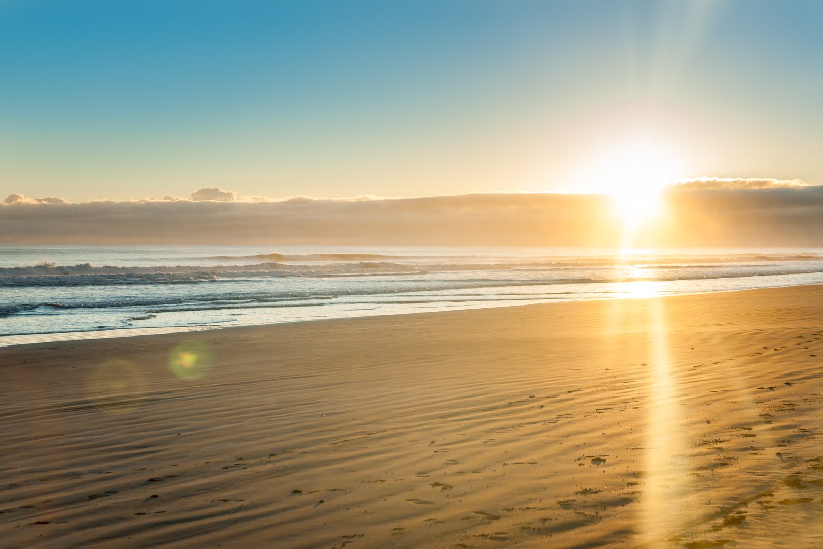 Sunrise over wide flat sandy beach at Ohope Whakatane, New Zealand.
