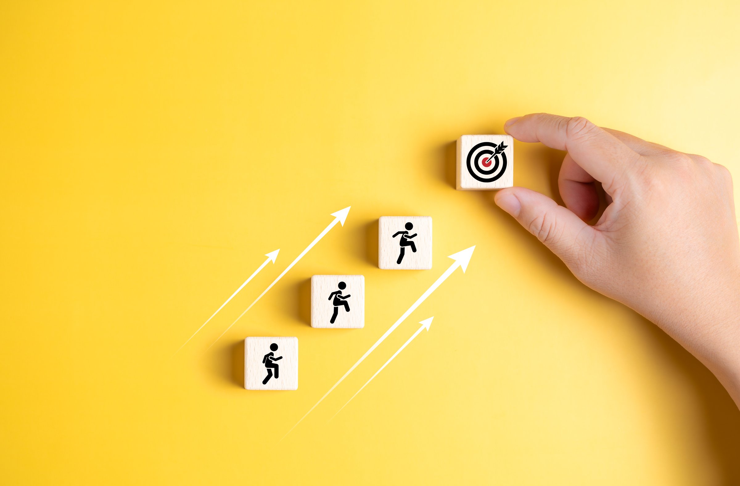 Life or business achievement and objective target for success. Rises upstairs to company target. Human icons climb on a stacked wooden block to the final goal. Human self-improvement and growth.