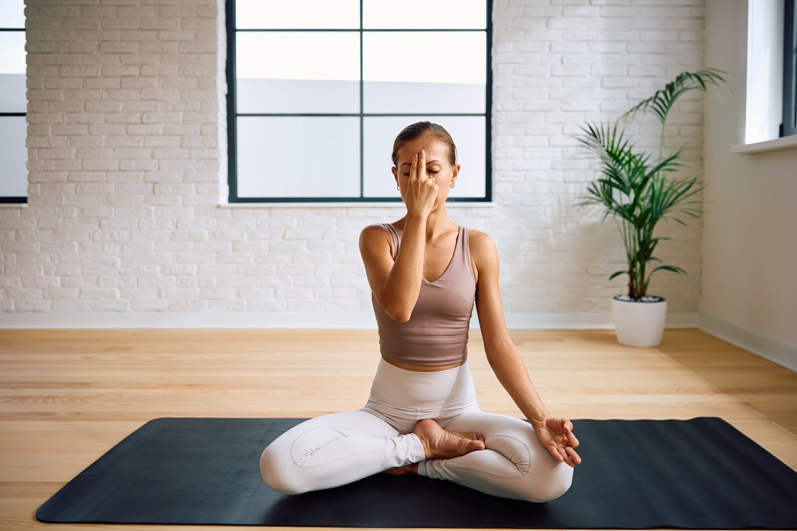Zen-like woman doing breathing exercises in Yoga studio. Copy space.