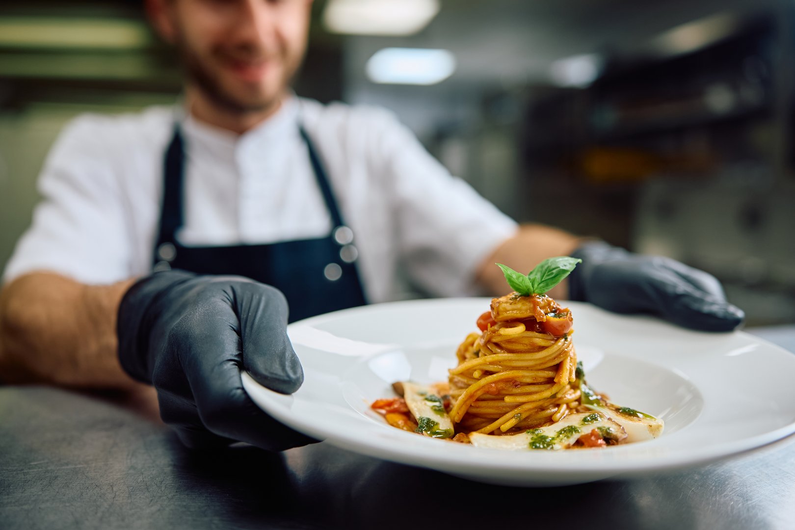 Close up of cook serving pasta in restaurant.