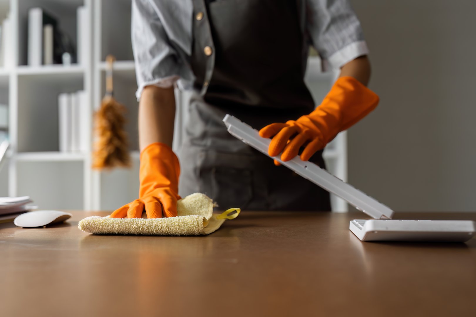 Woman maid cleaning and wiping the table with microfiber cloth in office.