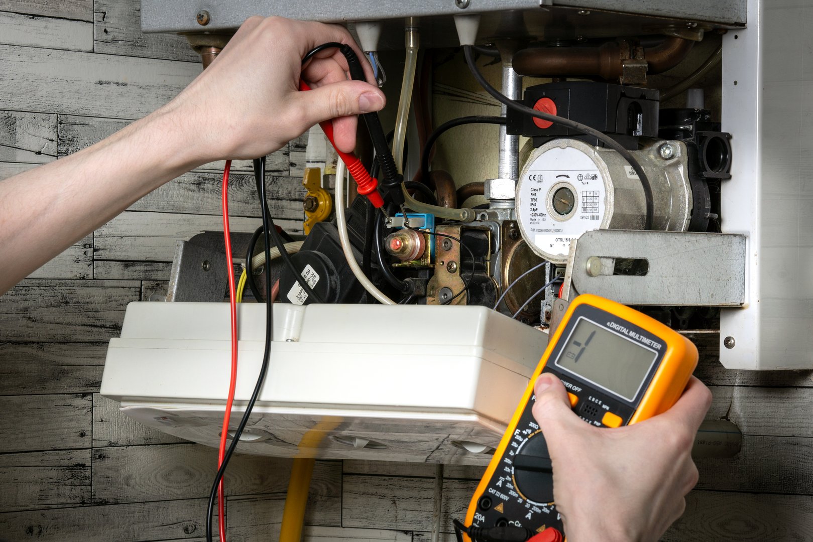 A young man is repairing an electric water heating boiler.