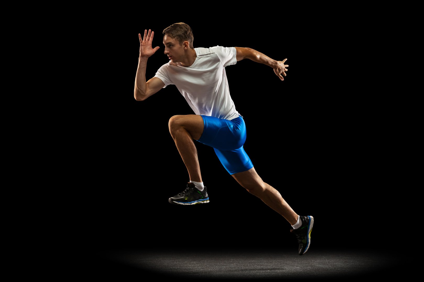 First number. One muscular, sportive man, male athlete, runner training isolated on dark studio background with spotlight. Concept of action, motion, youth, healthy lifestyle. Copyspace for ad.