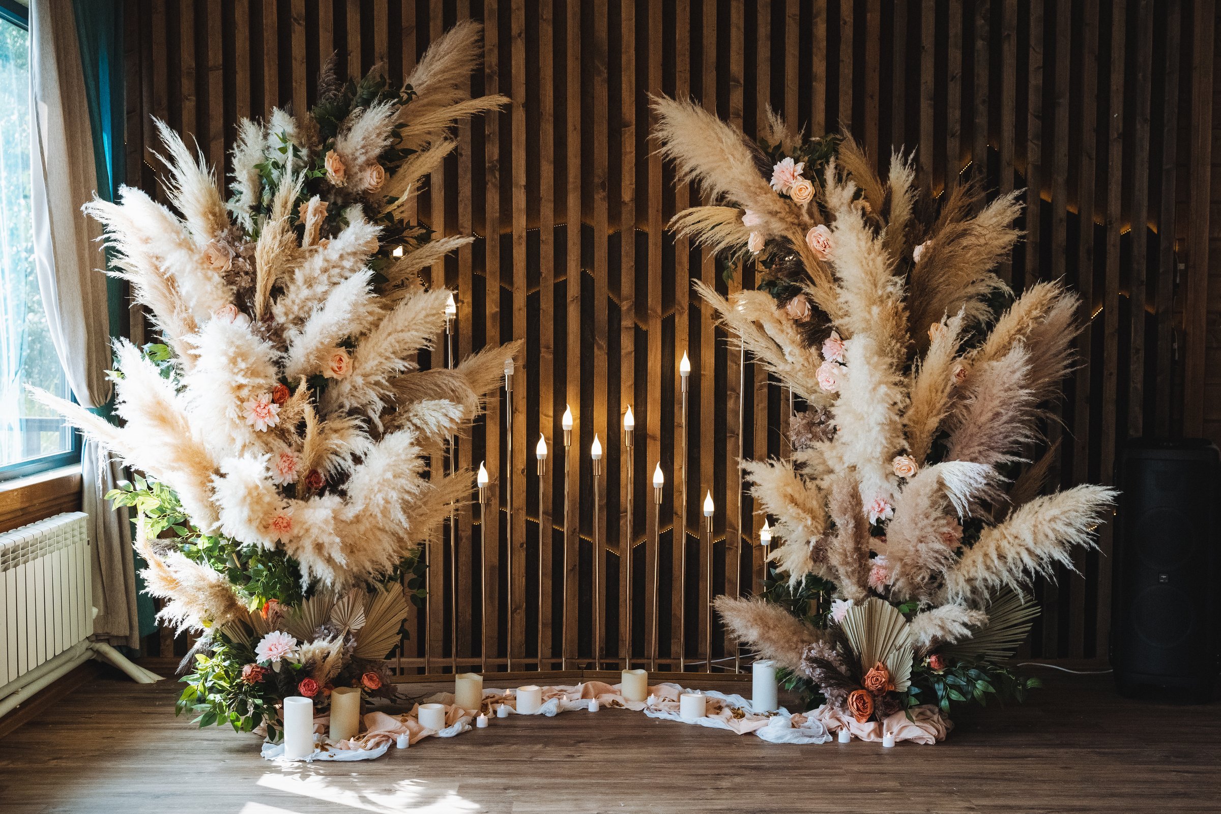 Stunning pampas grass floral arrangements beautifully create a romantic backdrop for a lovely wedding ceremony, which is illuminated by soft and enchanting lights