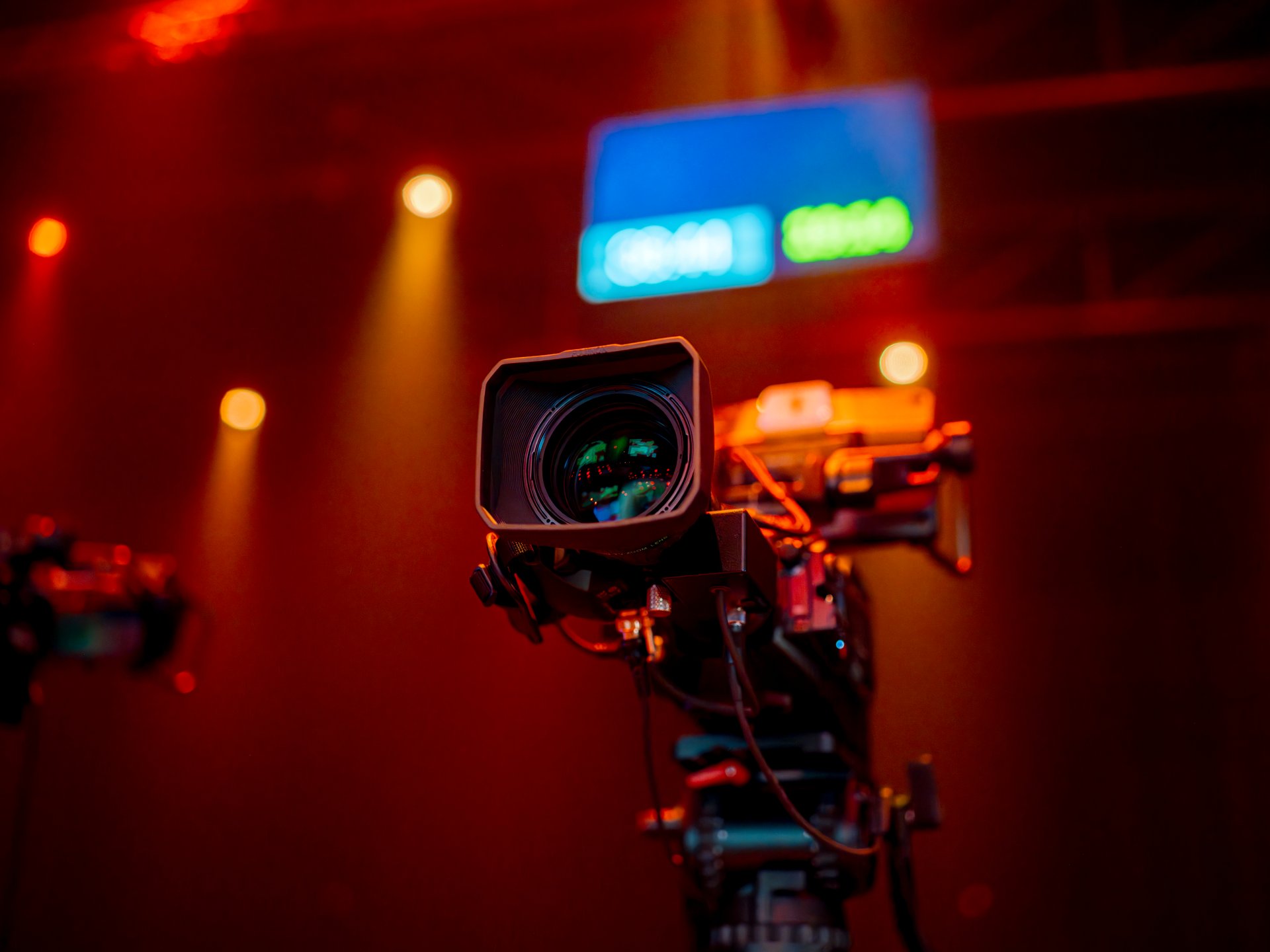 Cinema camera on rig with colored studio lighting and monitor in background