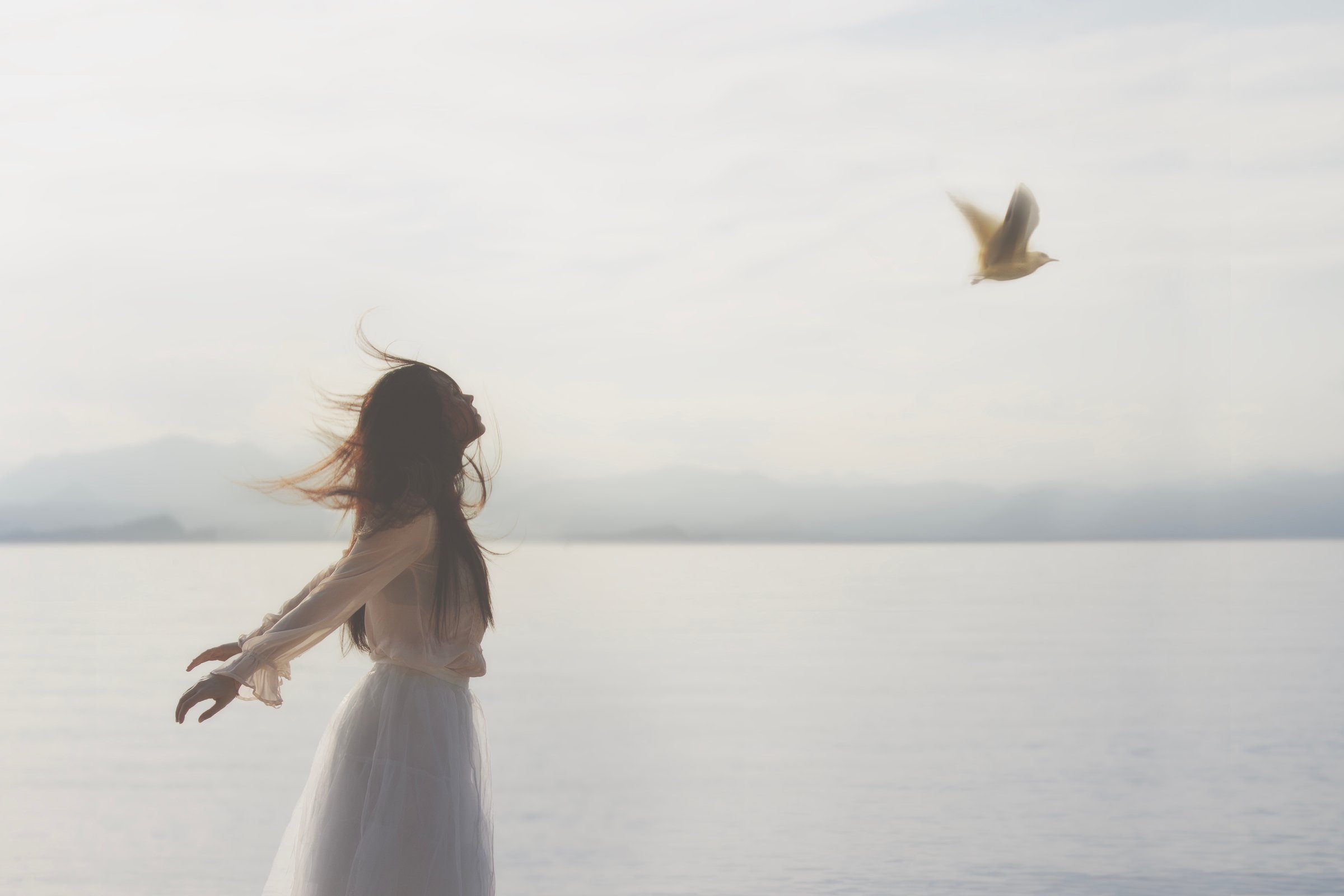 surreal woman with flying hair who is in perfect harmony with a flying bird, abstract concept