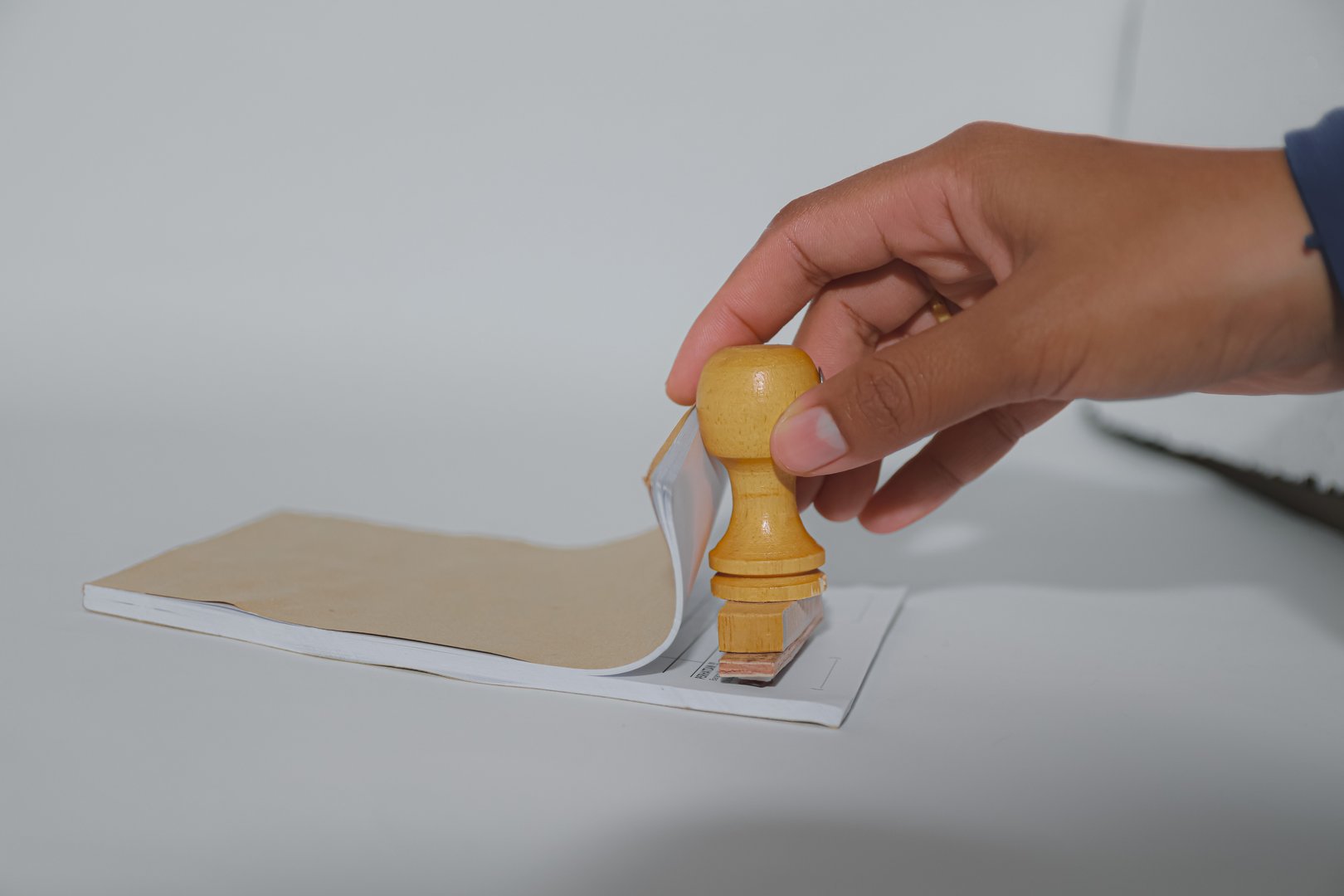 The hand that is holding the stamp is directed towards the note