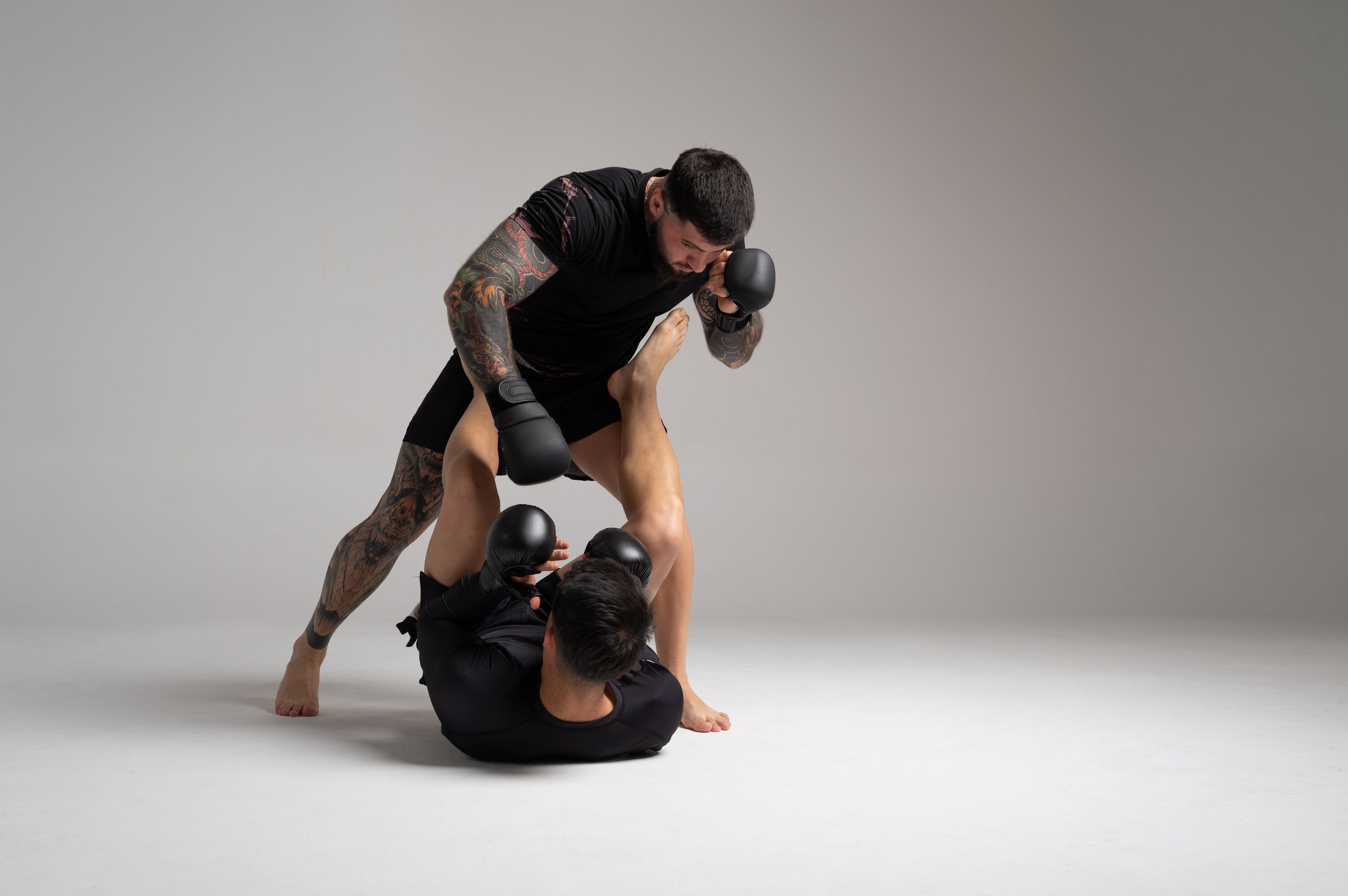 Two male mma fighters are sparring on a gray background, demonstrating a dynamic and powerful kick
