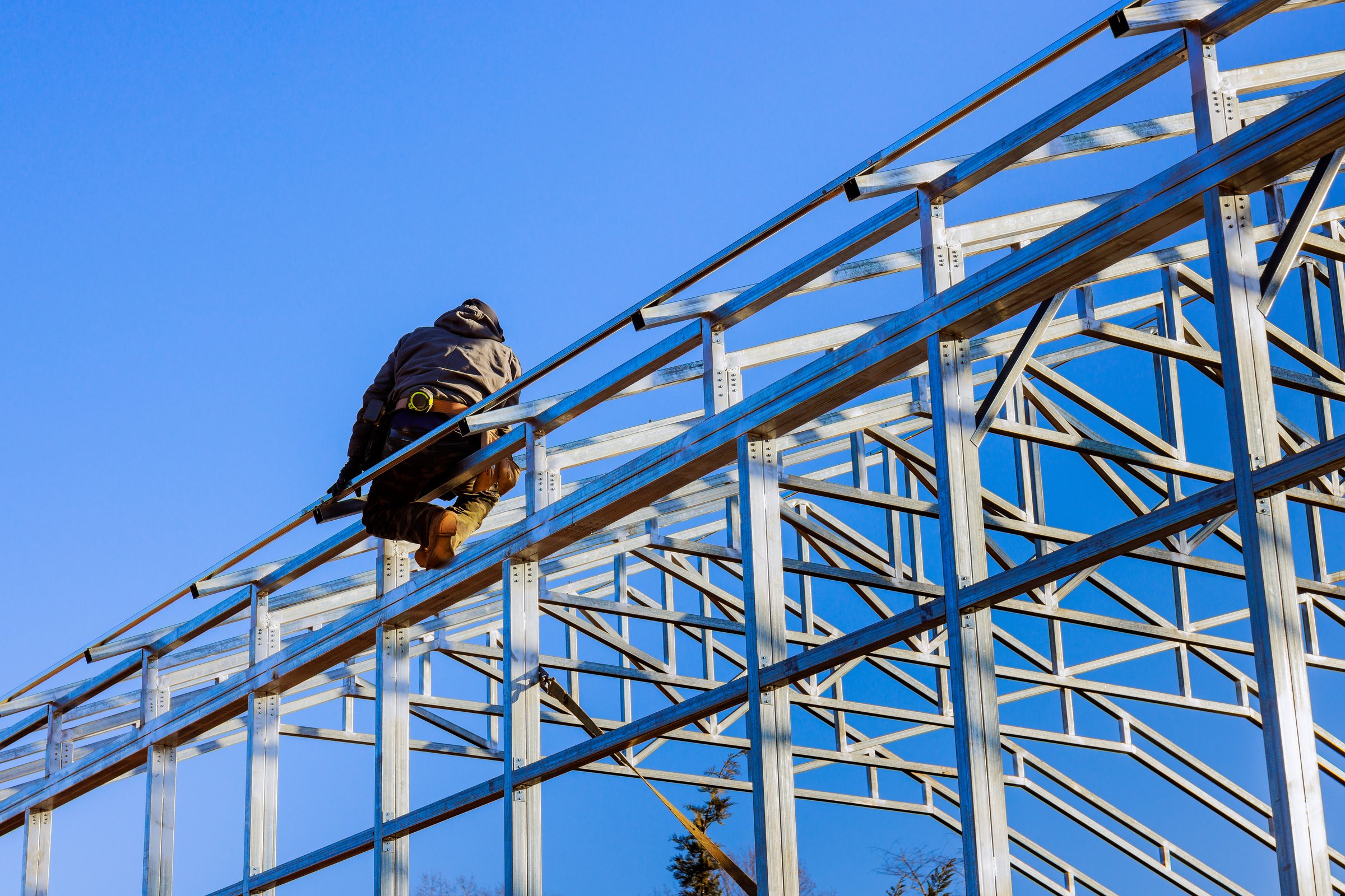 Construction worker is assembling framework metal structure of building commercial storage