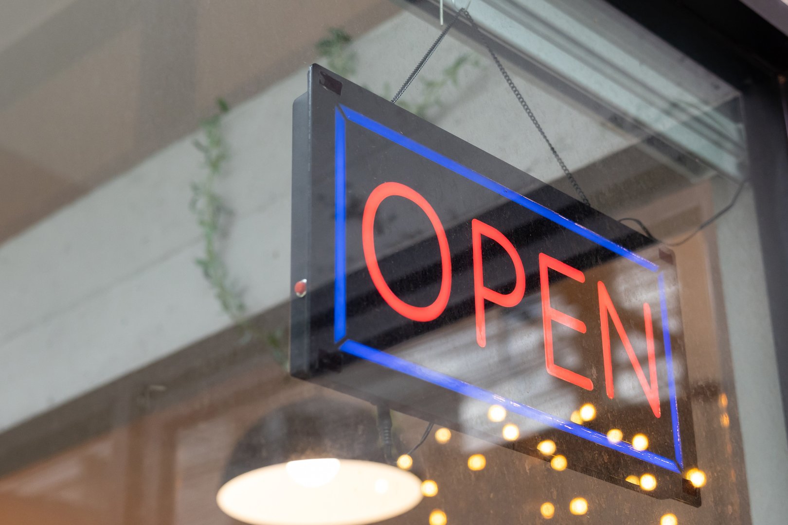 A neon sign that says Open hangs on a window. The sign is blue and red and is illuminated