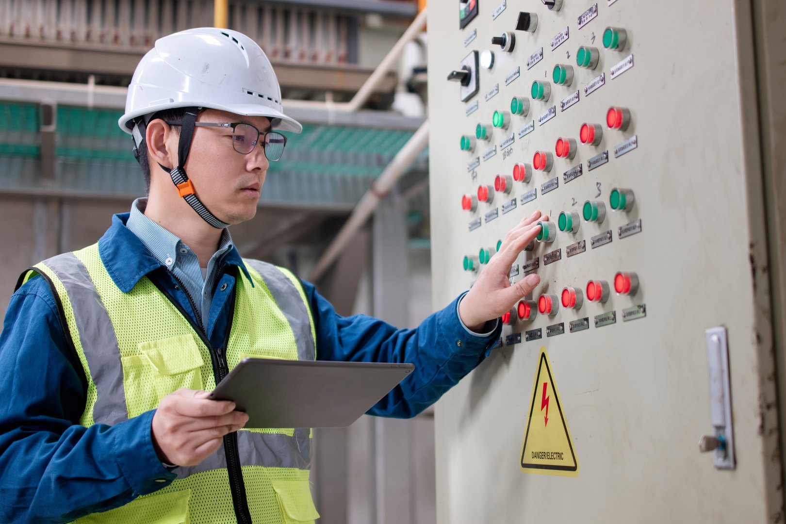 Asian engineers are working in the power distribution room.