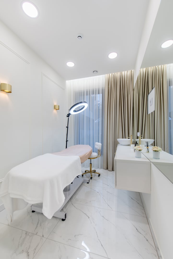 Elegant and minimalistic spa room interior with a treatment table, a ring light, and a serene ambiance.