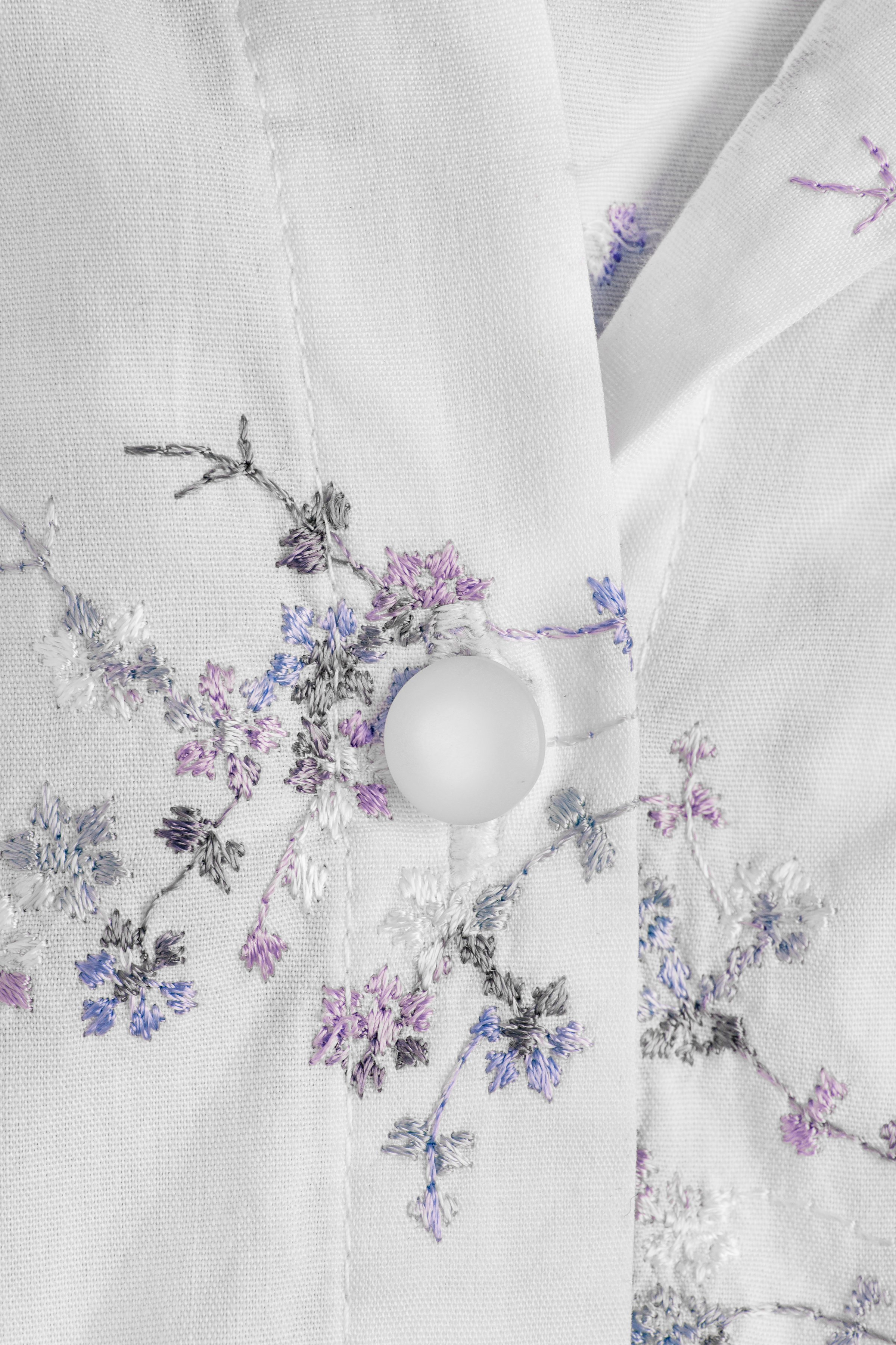 White shirt button on white embroidered shirt closeup as a background