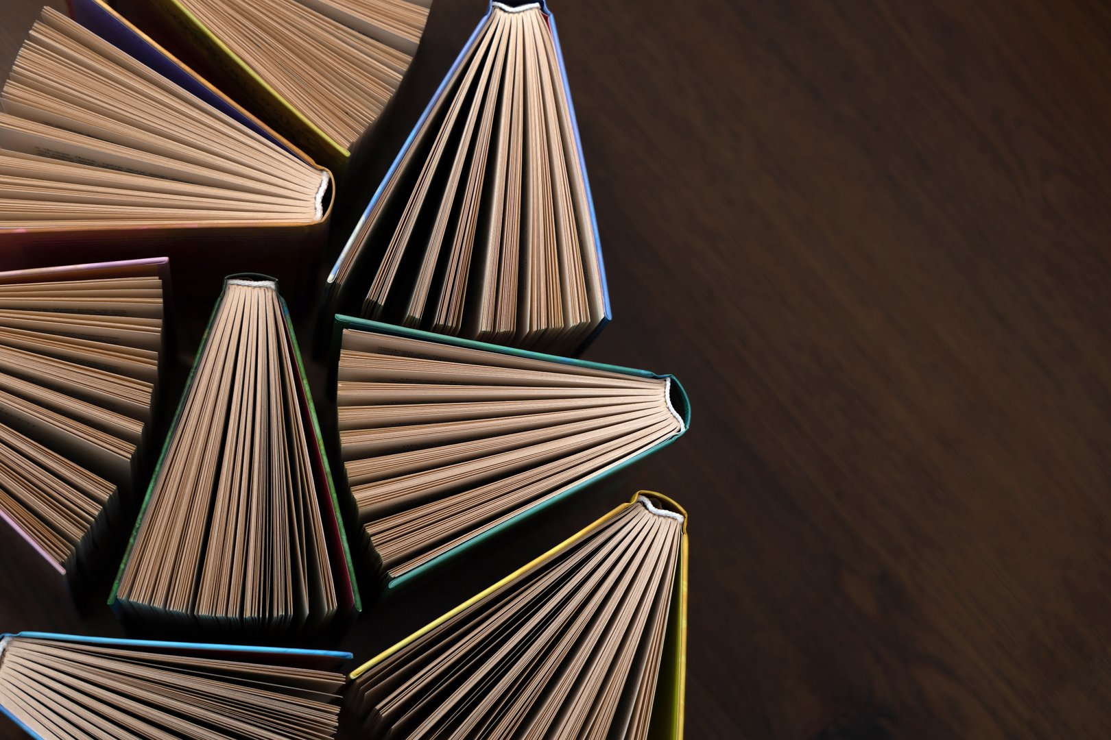 Hardcover books, colored covers textbooks, top view, on wooden floor. Books and reading are necessary for self-improvement, gaining knowledge and success in career, business and personal life..