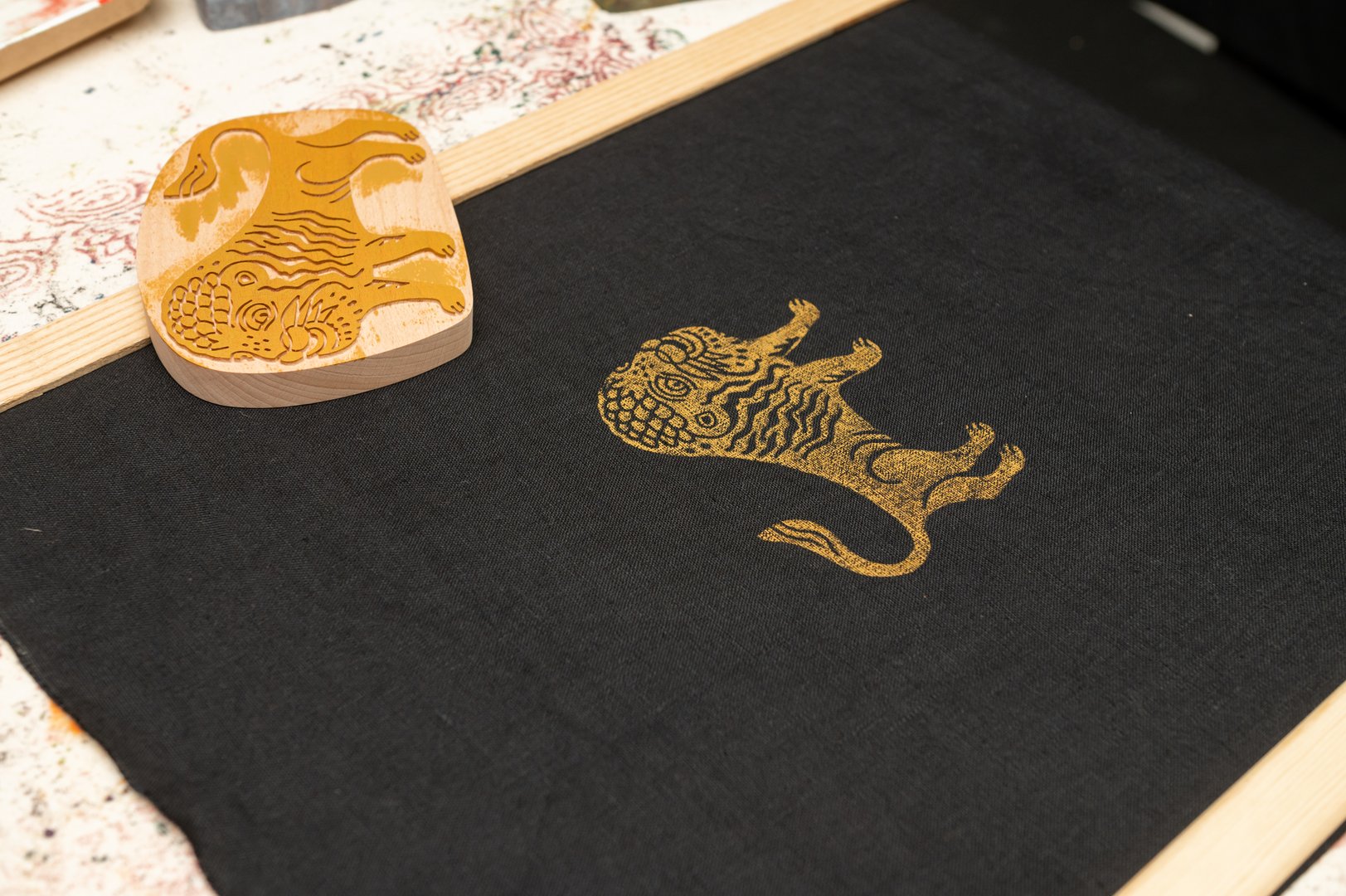 Traditional block printing on fabric with ornate lion design.