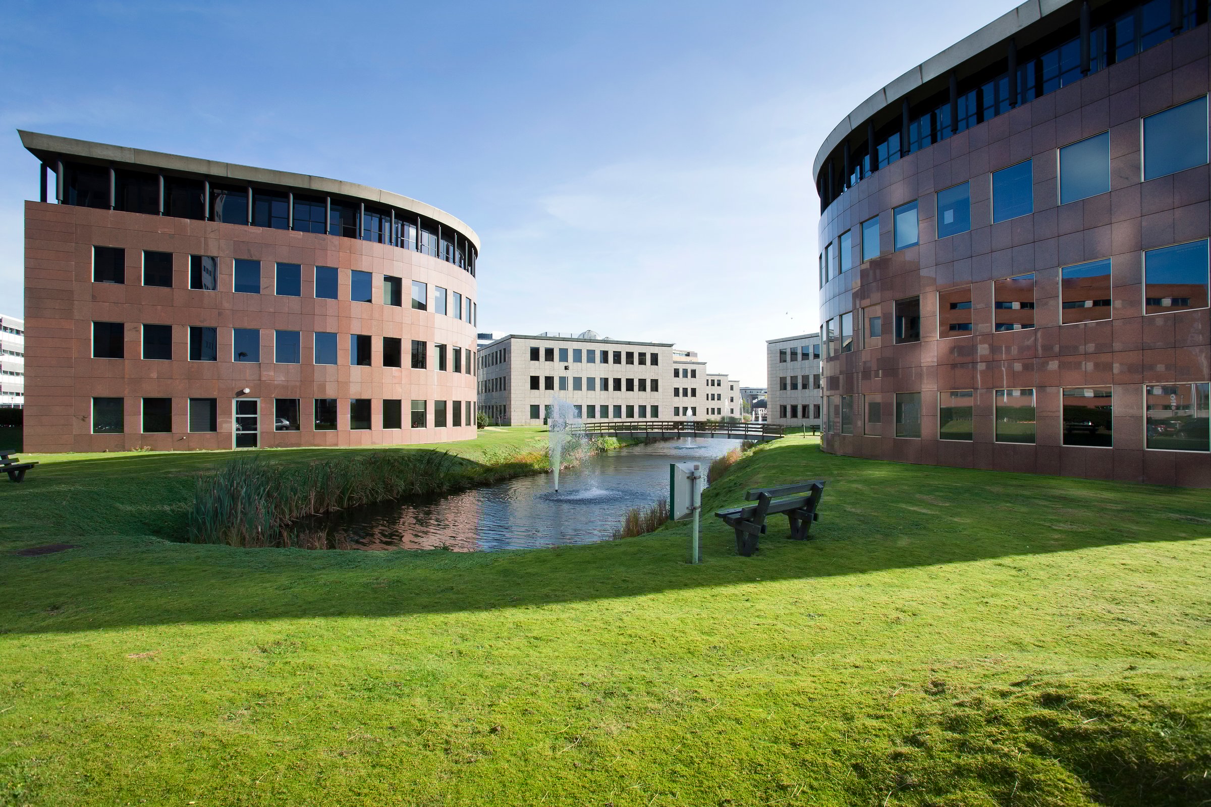 Office park with grass, water, fountain, bridge and benches