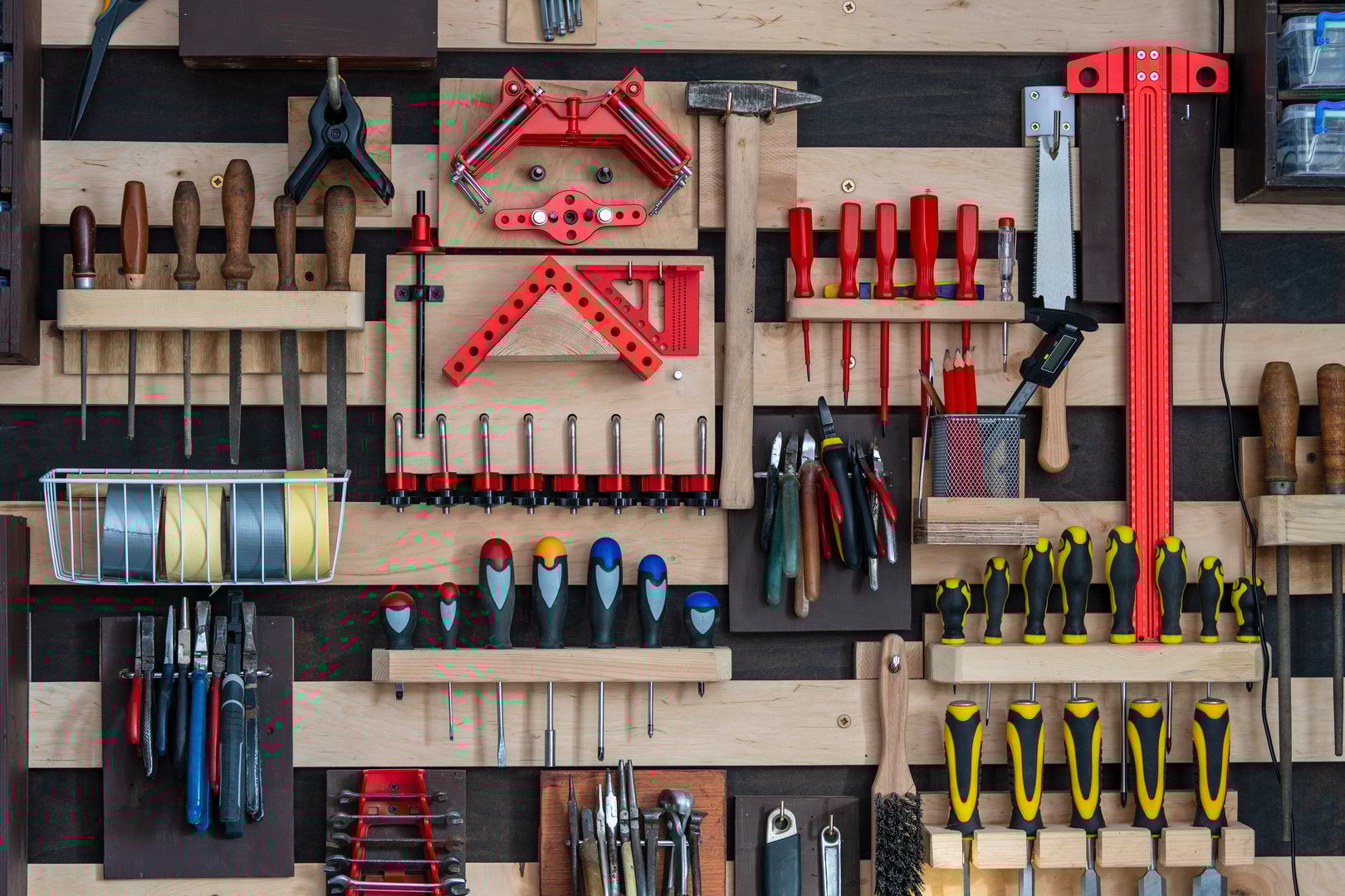 Various old work tools hang on the wooden wall in a home carpentry workshop