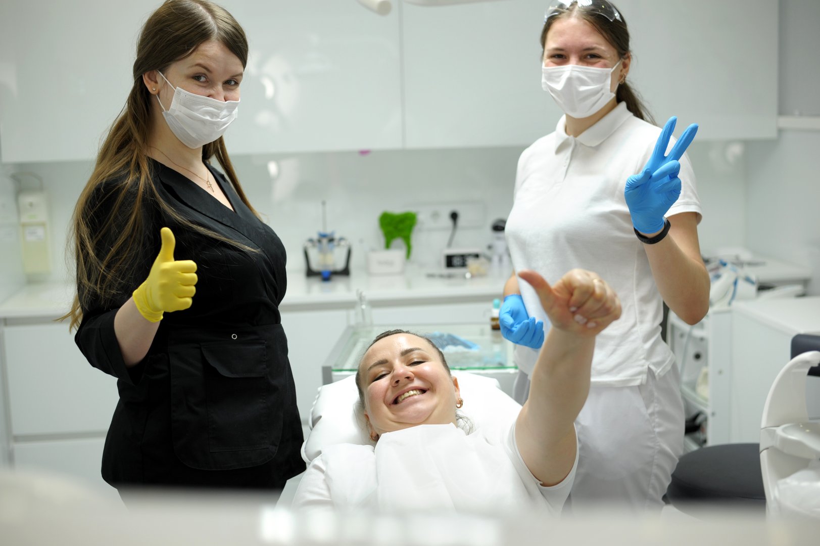 dental office satisfied patient showing thumbs up big class she liked service new technology doctor and assistant in masks are also happy with result of work smile joy dentist in black white