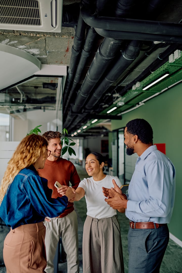 Diverse business colleagues at an office meeting, two women shaking hands, symbolizing agreement, partnership, and collaboration