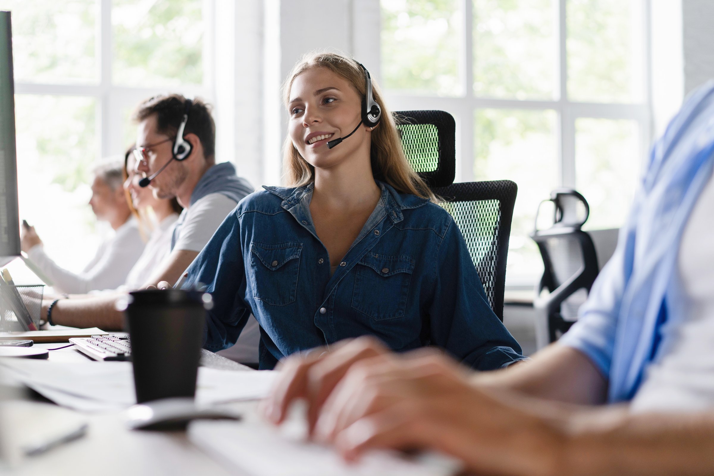 Young friendly operator woman agent with headsets working in a call center