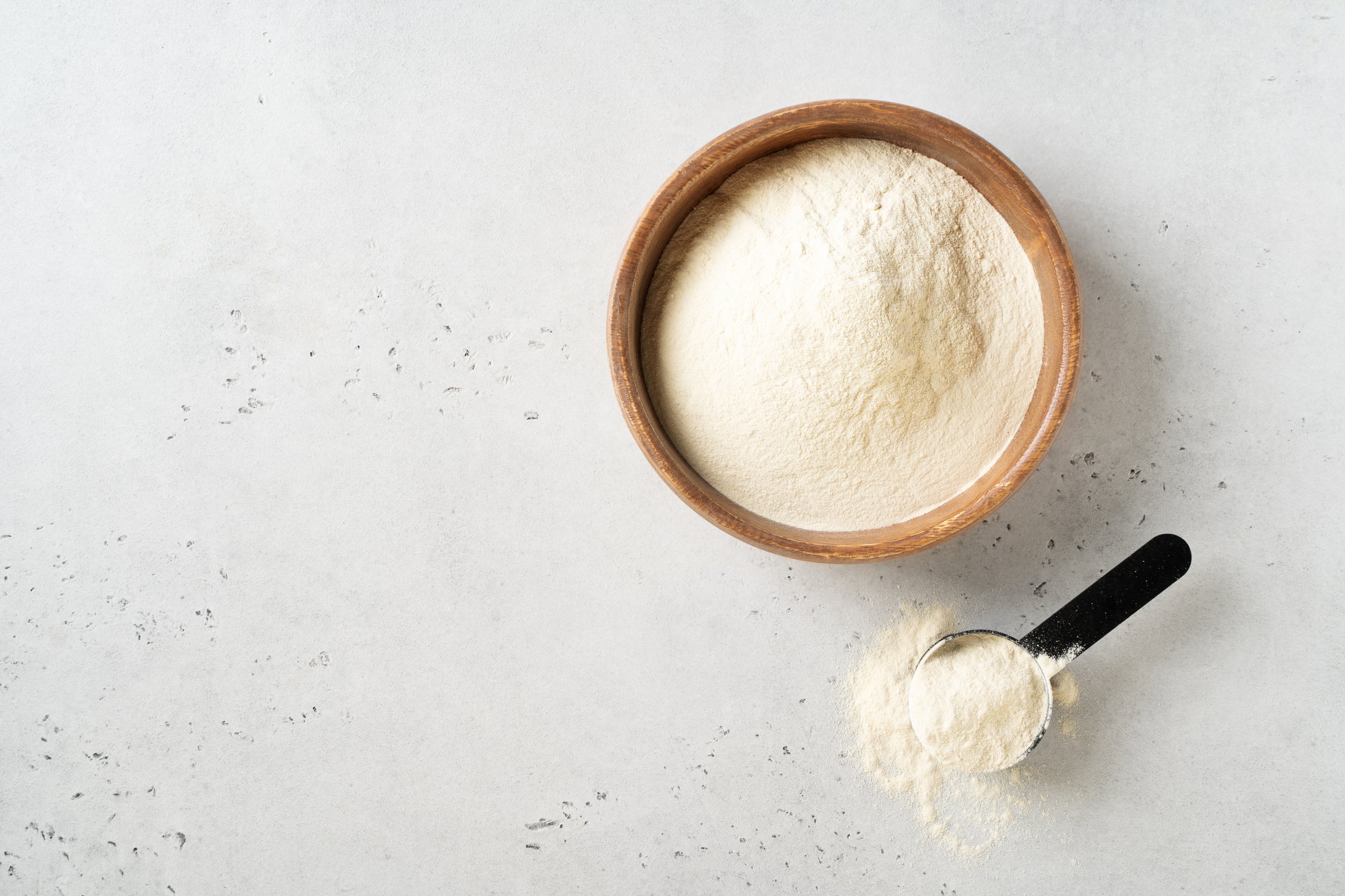 Different powder protein with scoop in plates on white background top view, copy space