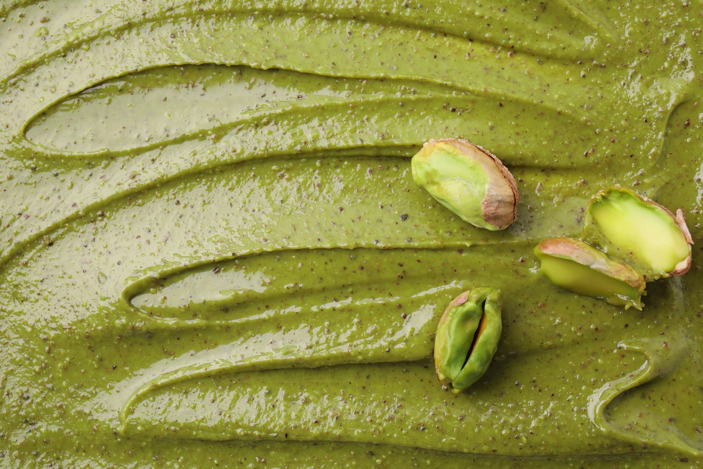 Fresh pistachio nuts on tasty cream, above view