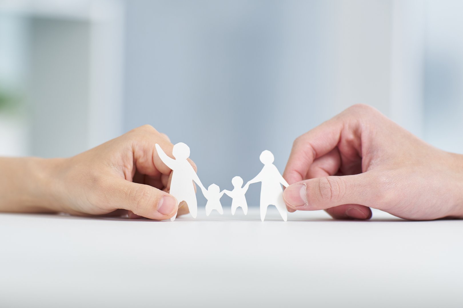 A couple's hands holding a family paper cutout