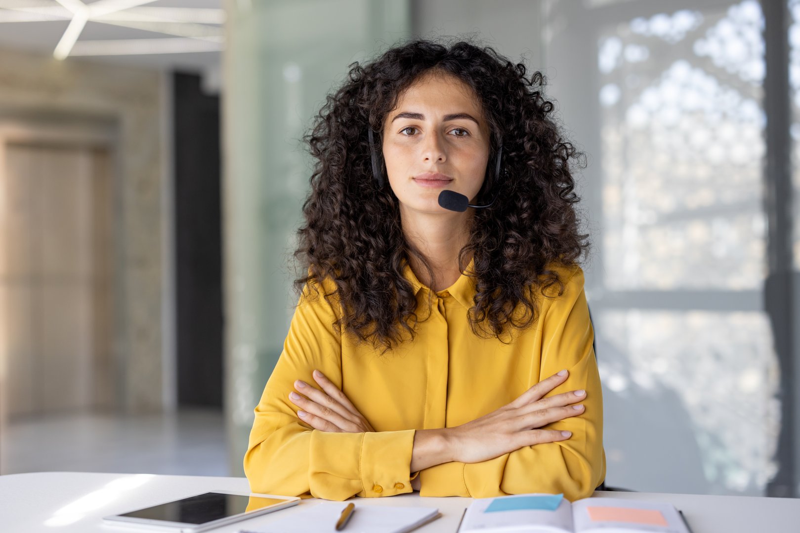 Webcam view, serious focused woman looking at camera with headset, businesswoman at workplace working inside office, listening to conversation remote conference.