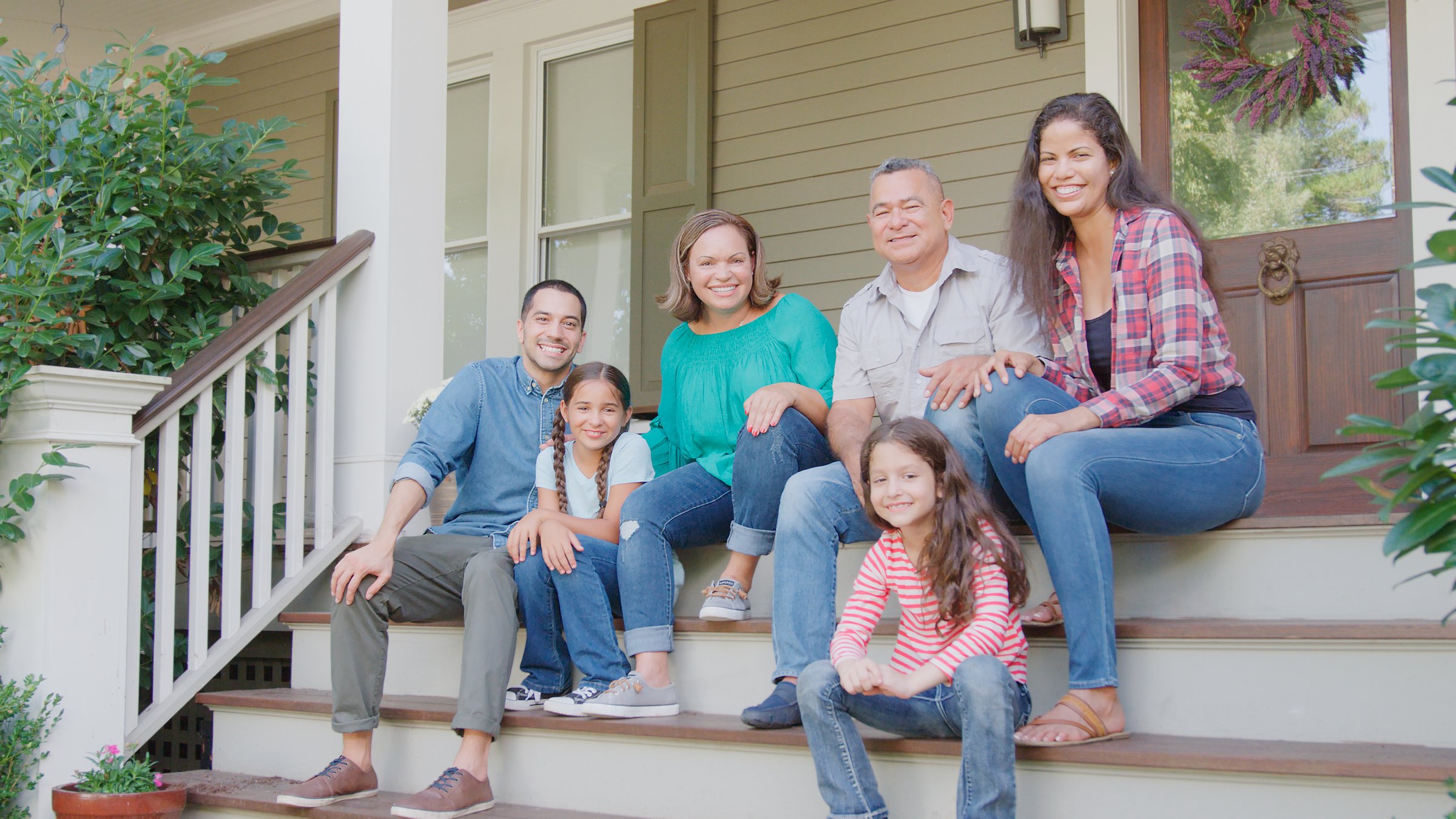 Portrait Of Multi Generation Family Sit On Steps Leading Up To House Porch