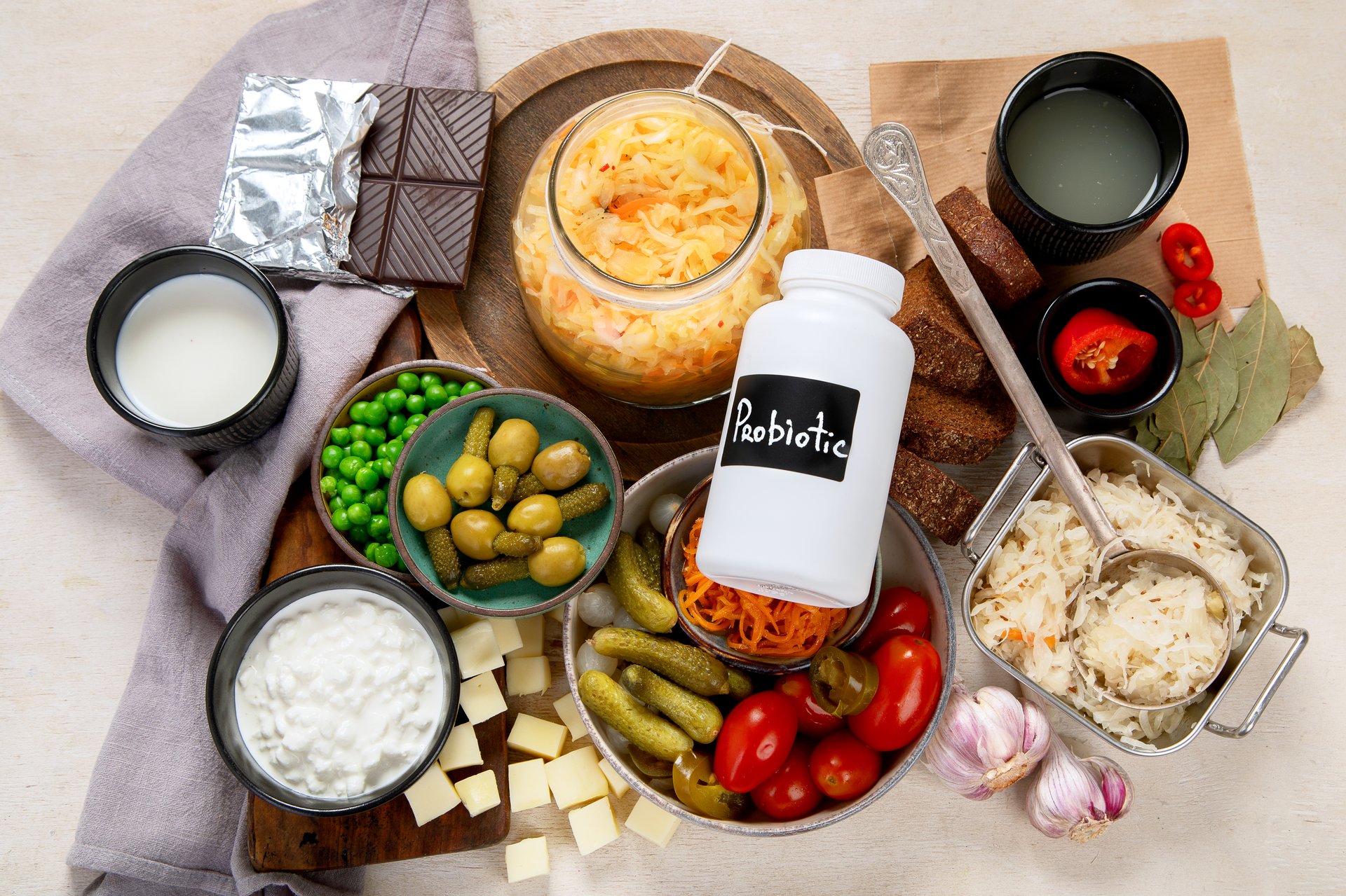 Probiotic food concept. Cabbage in jar, pickle, carrot on light wooden background. Top view