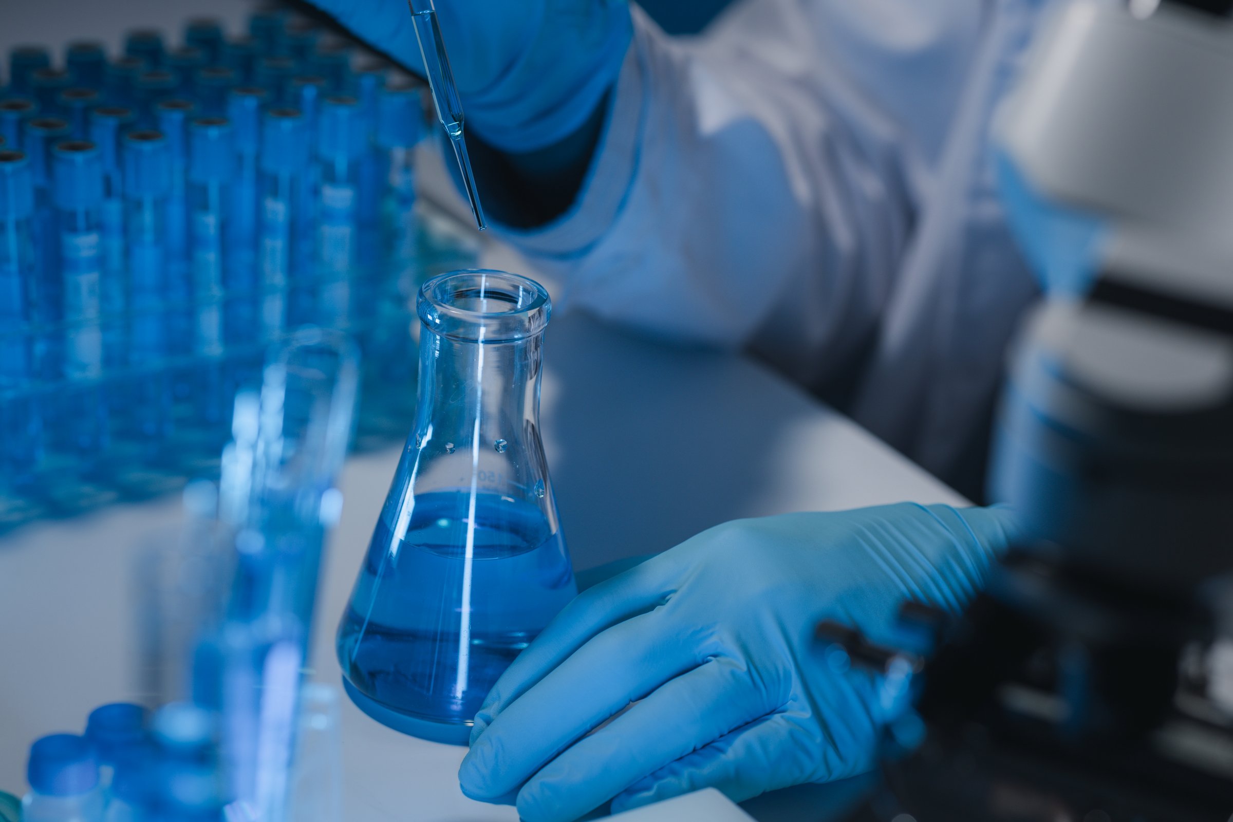 A researcher is carefully studying the liquid contained in a test tube because it is an important area of research, A scientist is using a tool to conduct a scientific experiment on liquids.