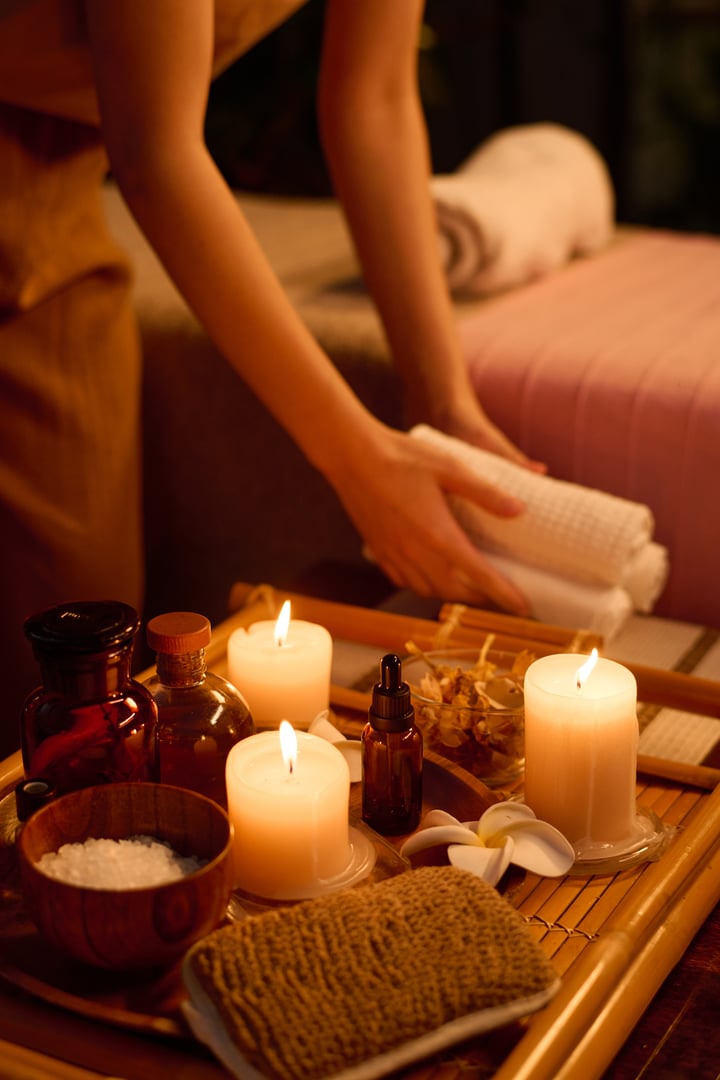 Vertical high angle shot of unrecognizable masseuse putting three towel rolls on coffee table fully prepared for spa therapy