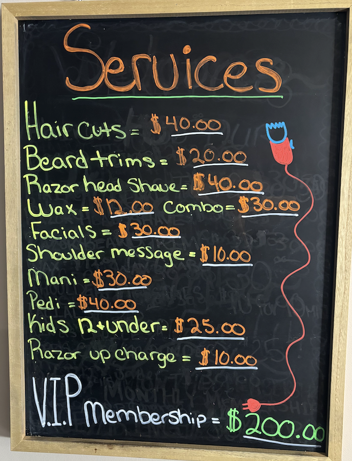 Chalkboard menu listing barber shop services with prices, including haircuts, beard trims, manicures, and VIP membership.