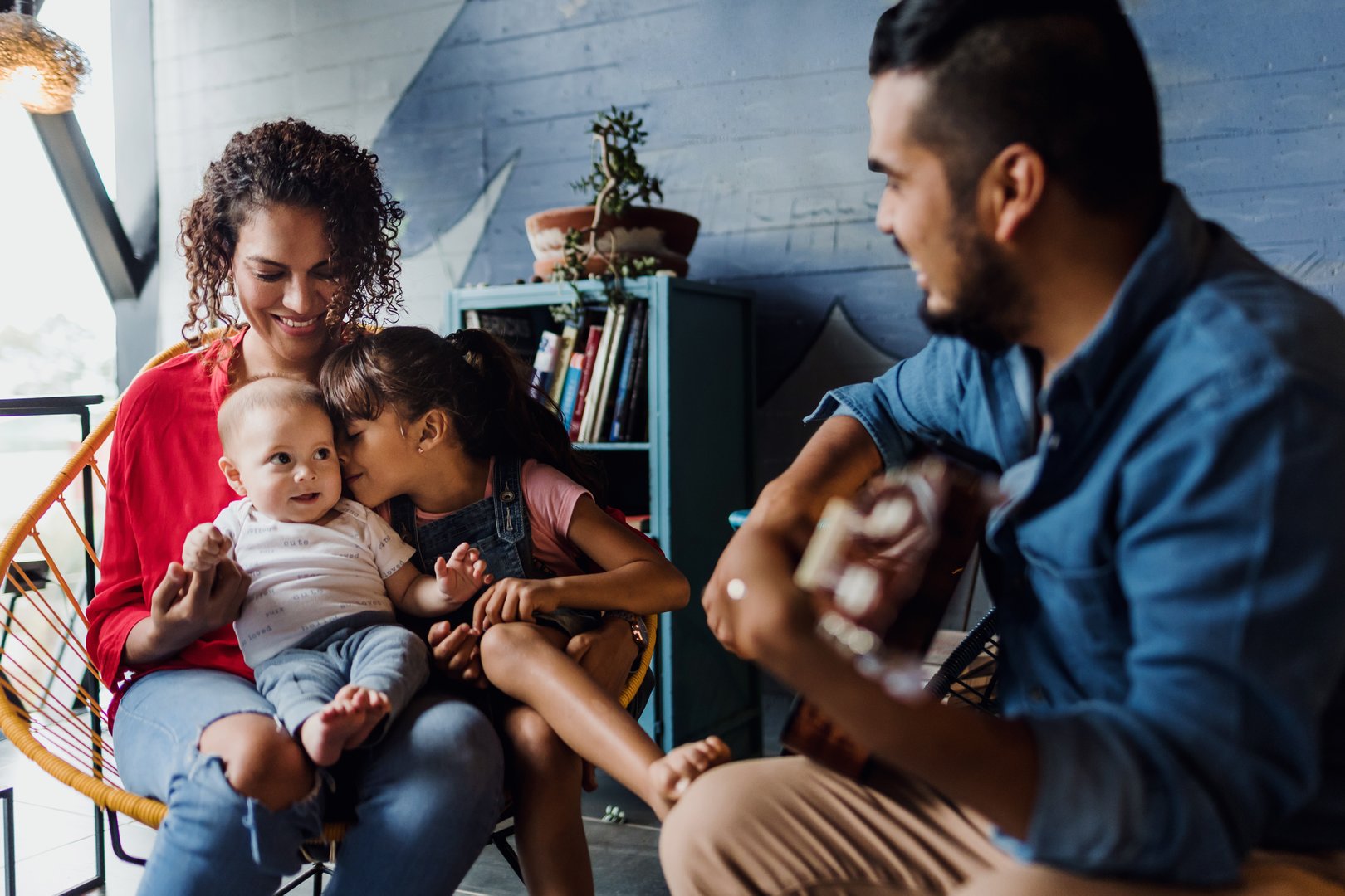 latin father playing guitar, singing and having fun with his family wife baby and daughter at home in Mexico Latin America, hispanic people