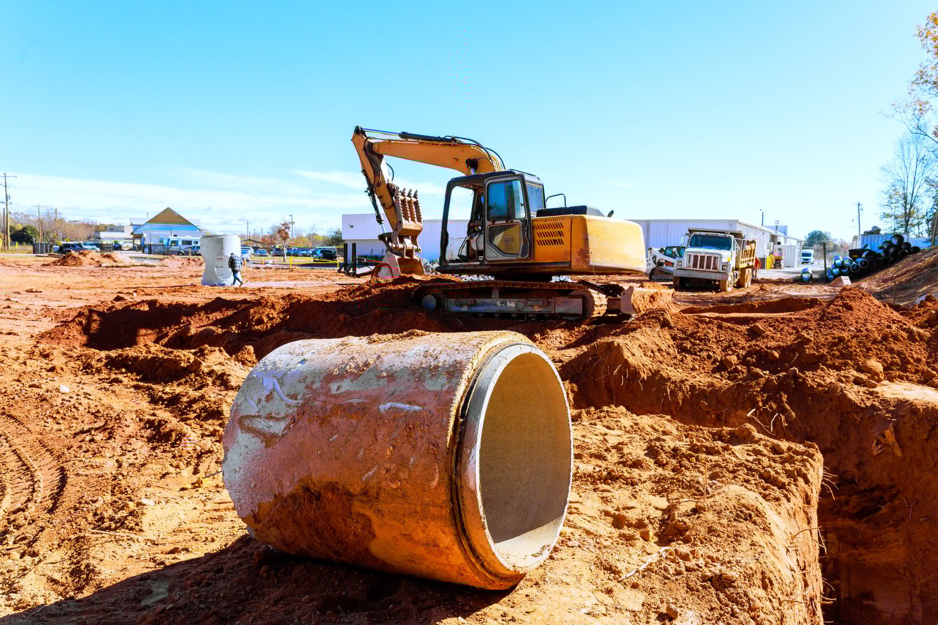 Heavy excavator machinery operates on construction site during earth moving as workers handle equipment materials
